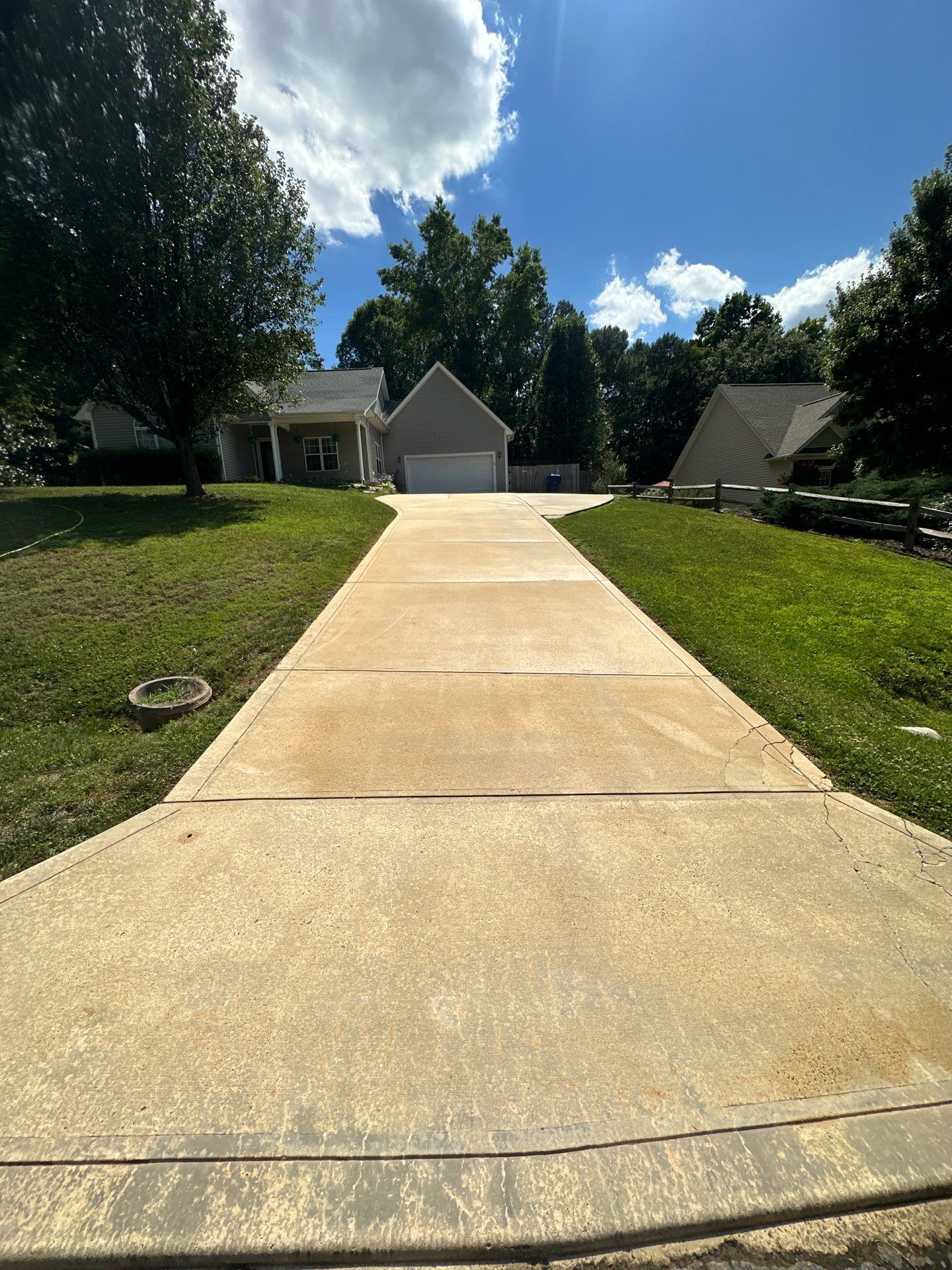 in the photo a pressure washing service is cleaning a concrete driveway the service being performed is removing dirt grime and possibly mildew or algae buildup from the surface of the driveway the effect of the pressure washing is evident as there is a clear contrast between the cleaned and yet to be cleaned sections the cleaned area appears lighter in color due to the removal of the surface contaminants while the untreated area is visibly darker and soiled indicating where the company will likely clean next