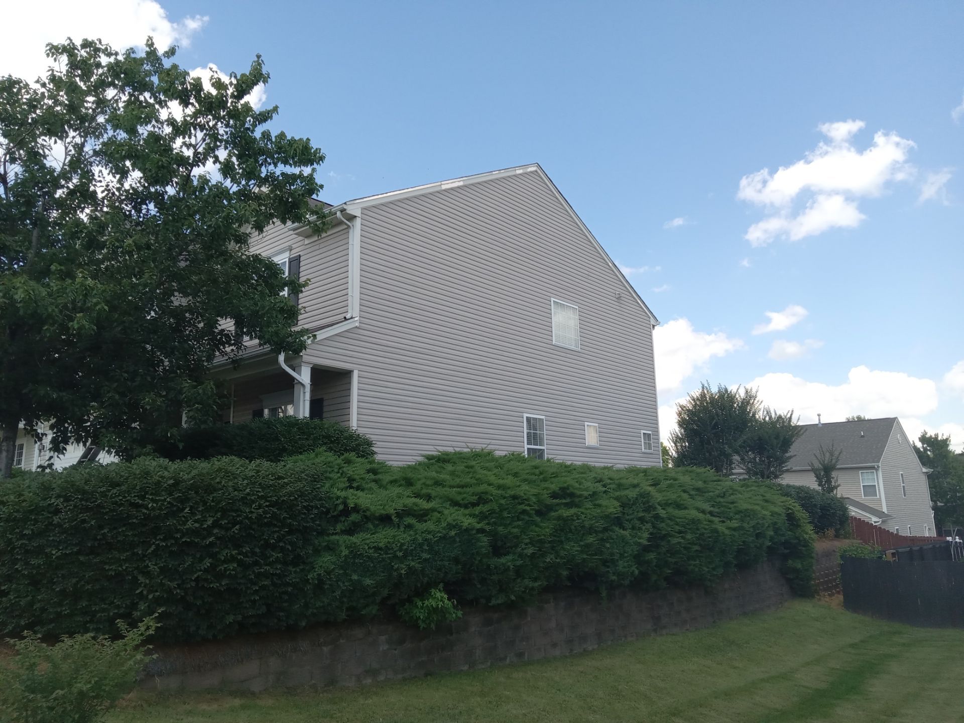 the image shows the exterior of a residential building the pressure washing service being provided likely includes cleaning the siding of the house removing dirt grime mildew and potential mold growth from the surface the service may also extend to cleaning the gutters and downspouts which accumulate debris and can cause water damage if not maintained high pressure water is used to effectively clean the surfaces without the need for abrasive chemicals ensuring the building exterior is clean and well-maintained