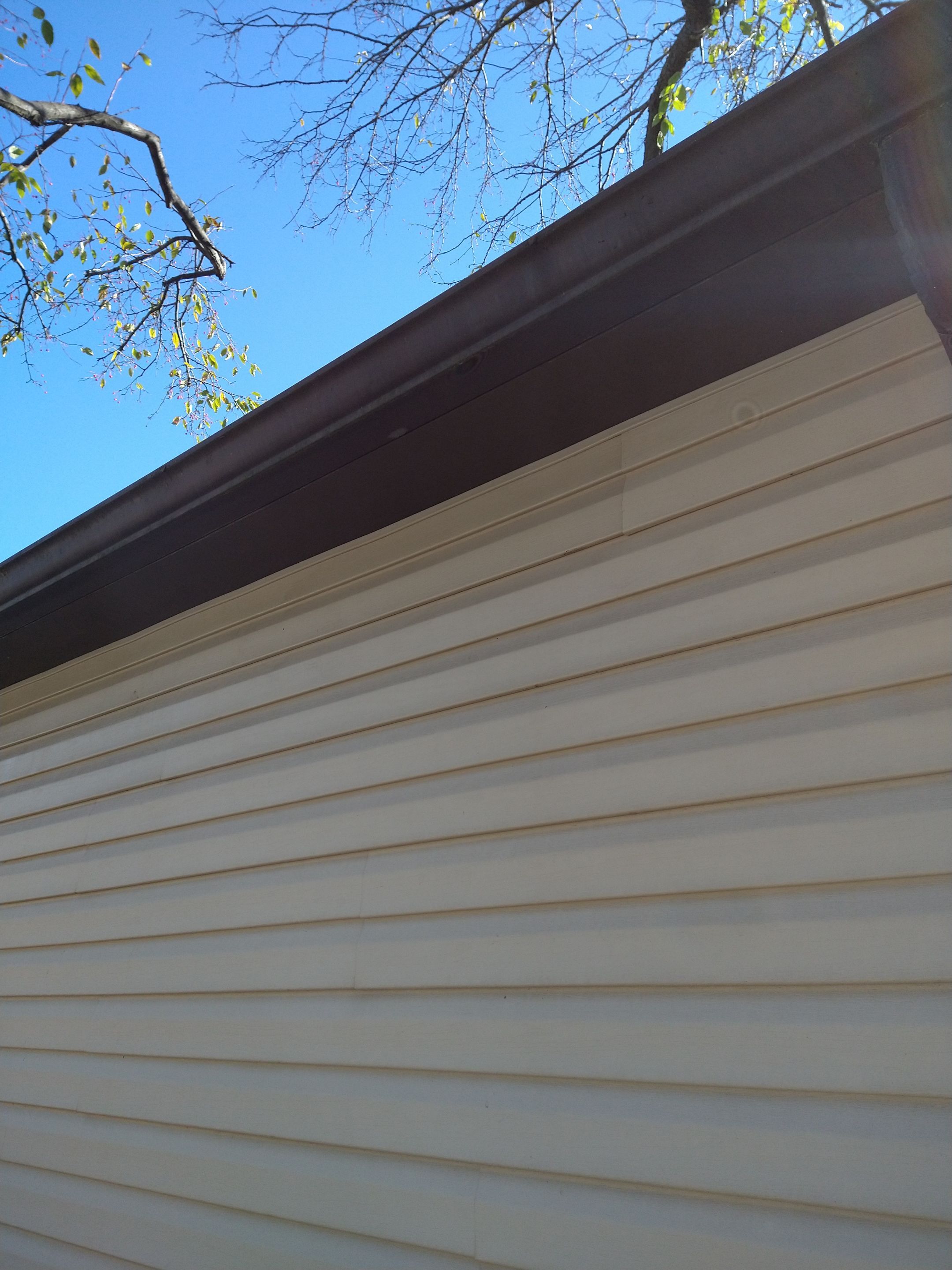 Siding Installation using Norandex woodsman dl-5 white woodgrain vinyl by Absolute Roofing and Construction