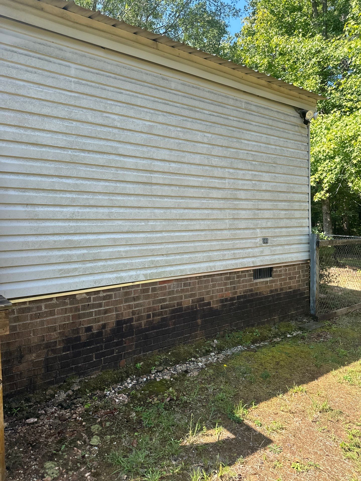 the photo shows pressure washing service being performed on dirty siding and brick removing grime and mold from the surfaces