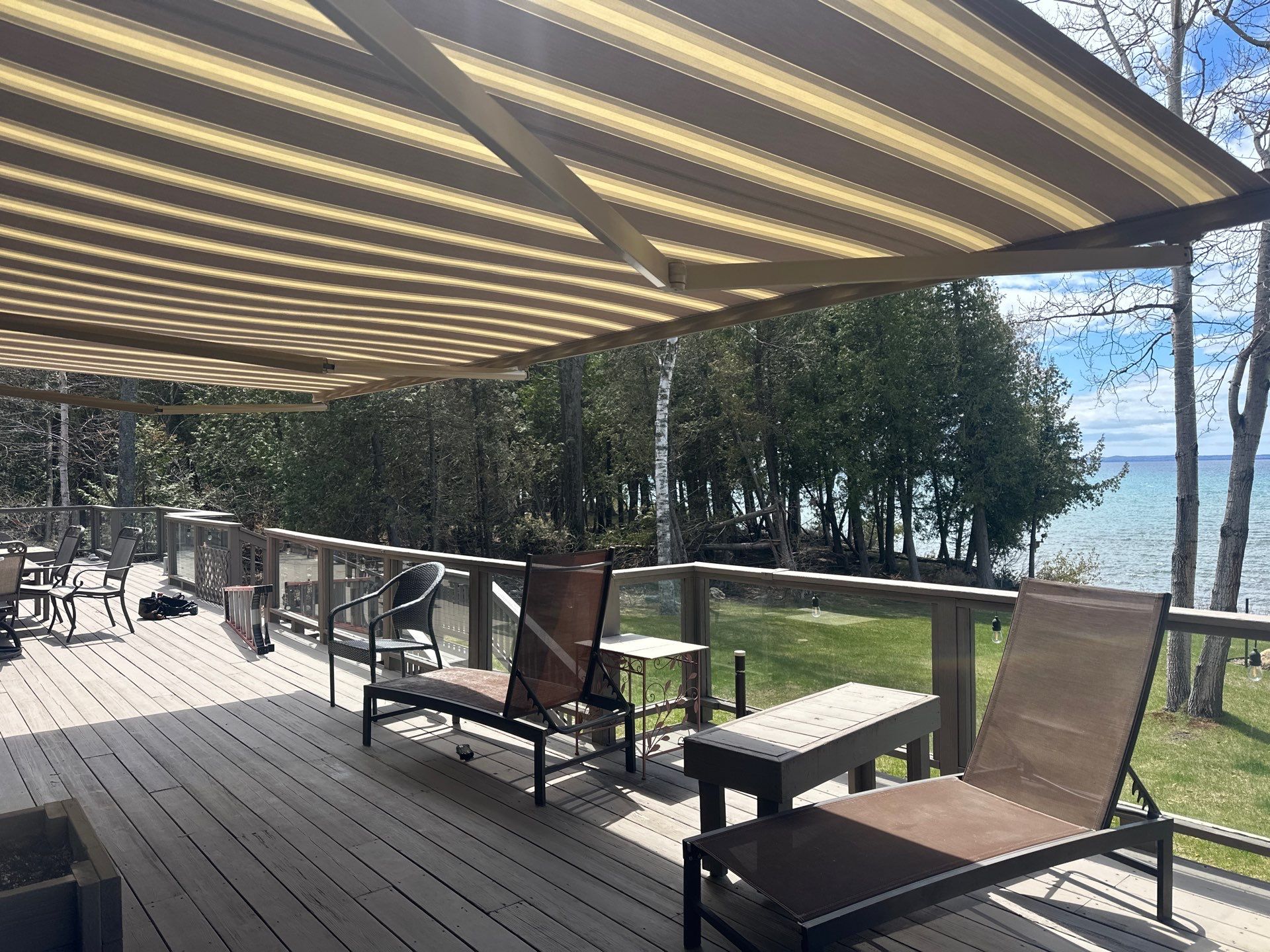 Retractable Striped Awning Installation for Waterfront Composite Deck in Charlevoix by Rainbow Seamless Systems