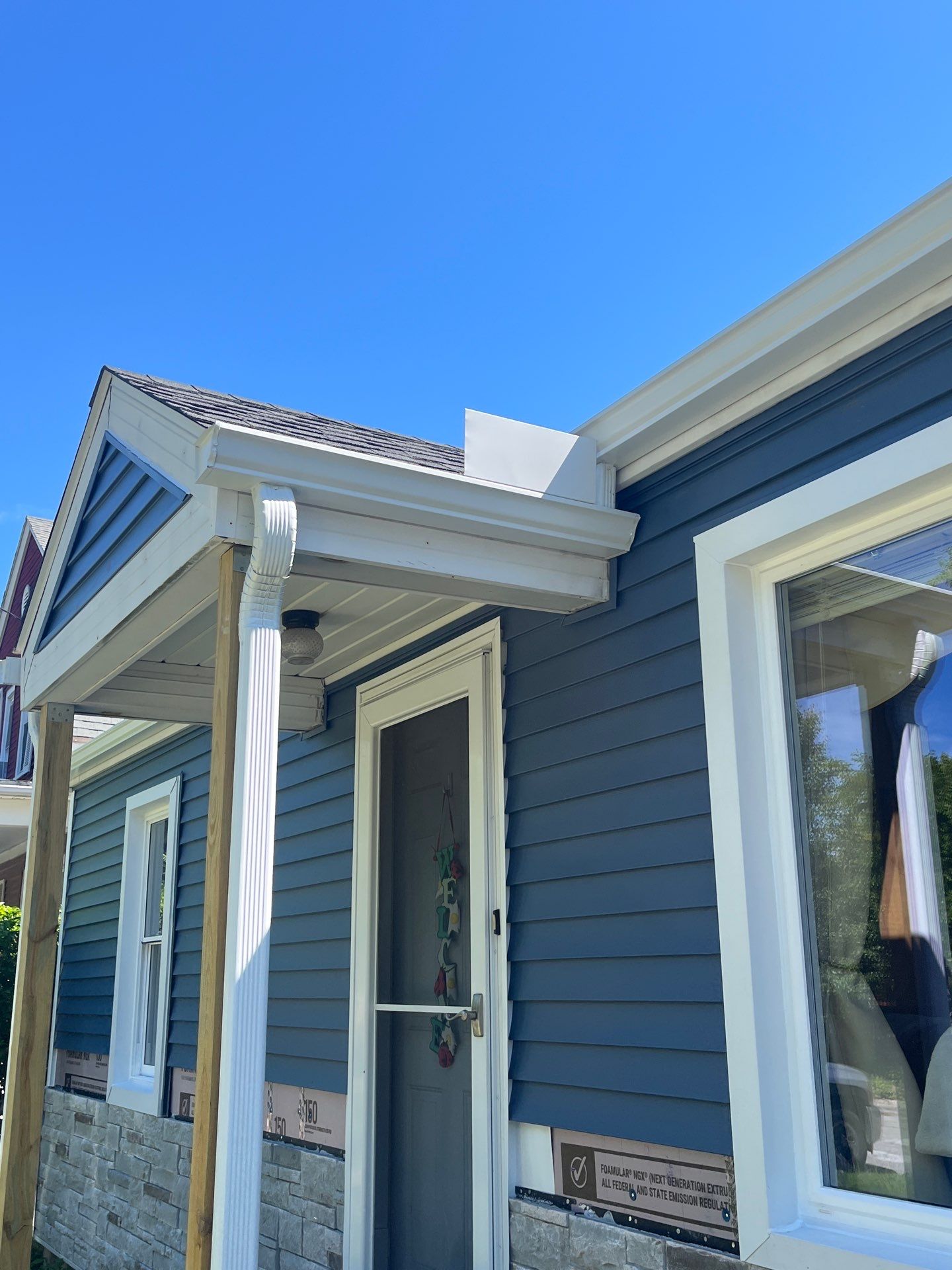 Blue Vinyl Siding and Versetta Stone Exterior Remodel in Bay City by Great Lakes Home Design LLC