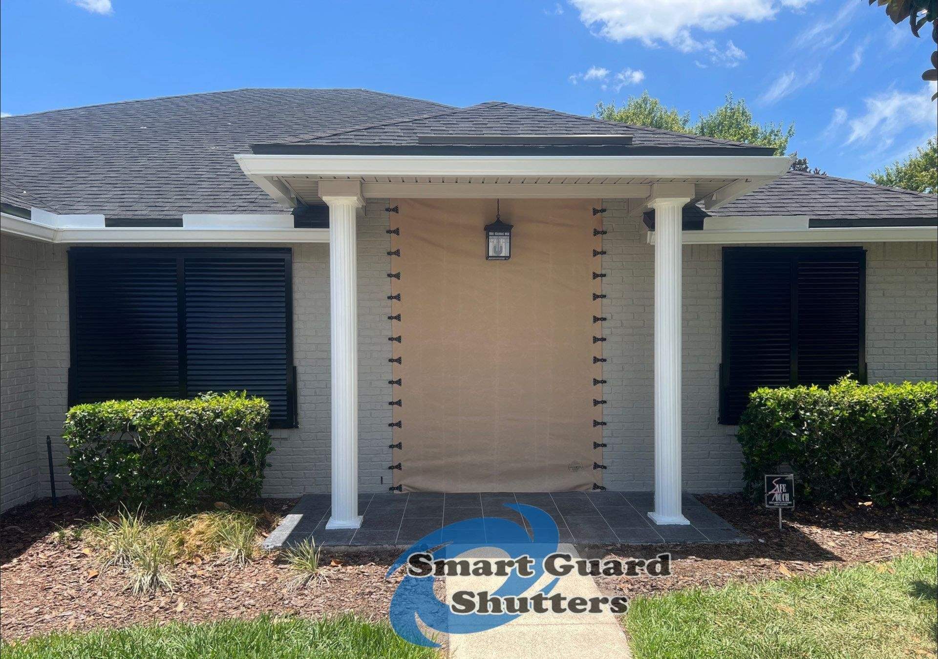 Hurricane Protection using Bahamas in Traffic Black and Fabric in Tan by Smart Guard Shutters