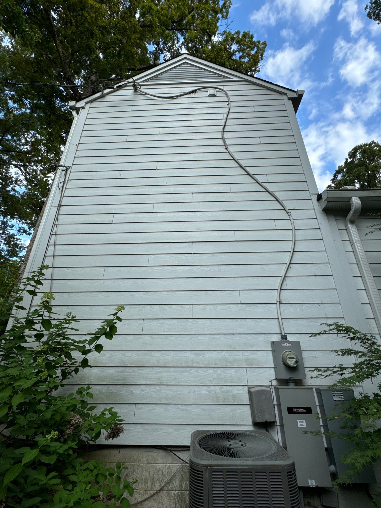 pressure washing the exterior siding of a house to remove dirt and mildew buildup