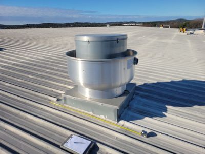Wide view of industrial metal roof with ventilation unit