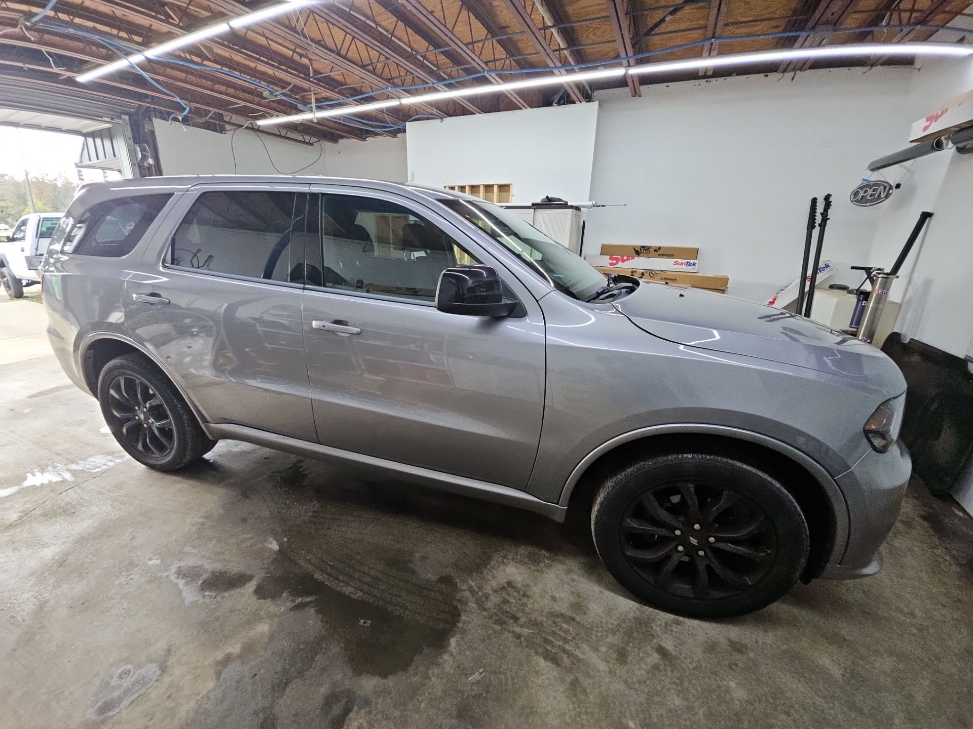 the image shows a silver suv likely undergoing window tinting service the vehicle has its windows partially covered with a film to enhance privacy reduce glare and improve aesthetics the tinting process involves cleaning the glass cutting the film to size and applying it carefully to avoid bubbles and imperfections the suv is likely inside a shop where the tinting is being performed ensuring a controlled environment for the best results