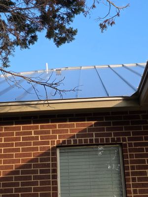 Close up of standing seam metal roof on brick wall.