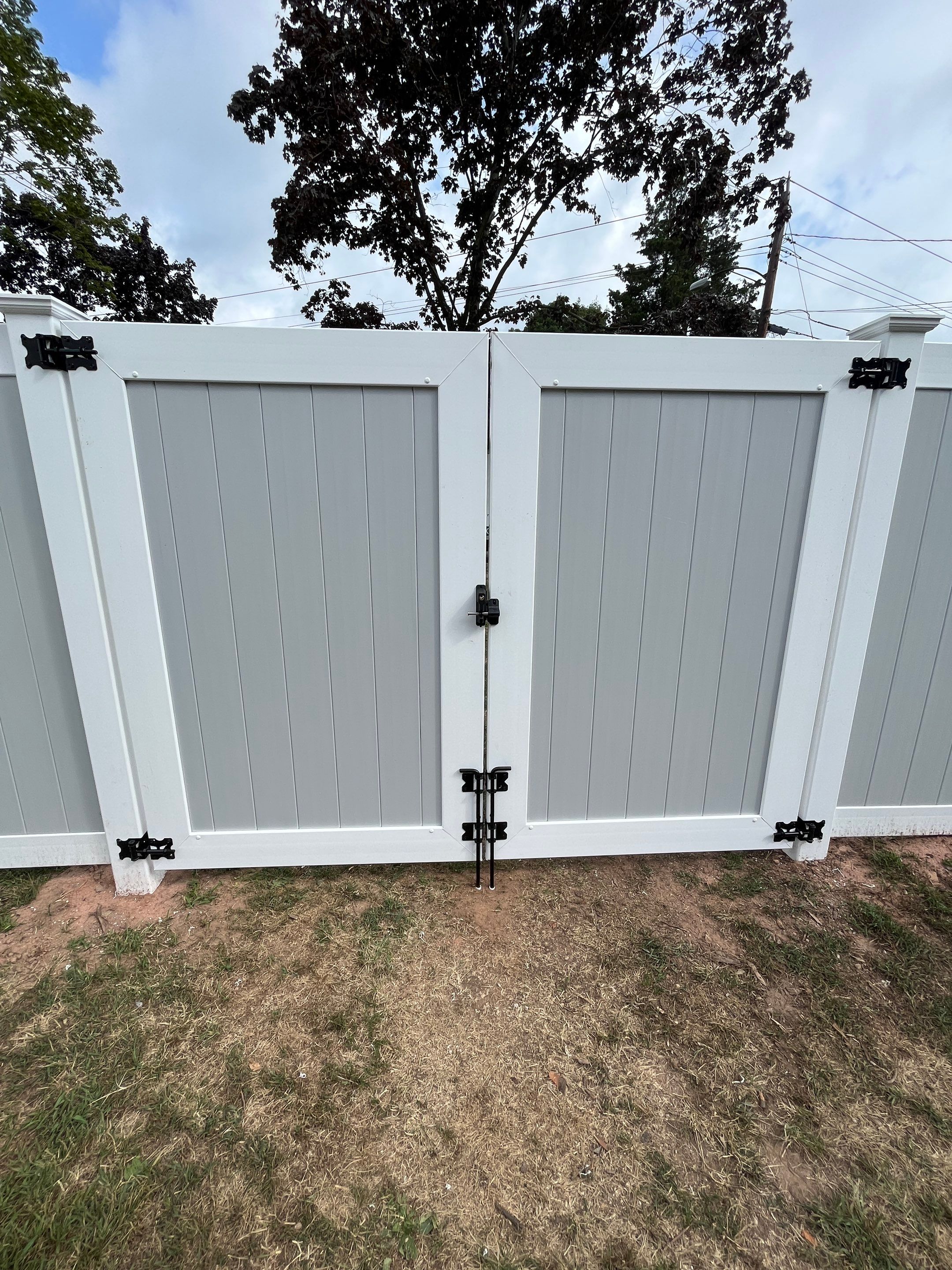 New Vinyl privacy fence with double gate. In two tone gray and white coloring. by DiGiorgi Roofing and Siding Inc