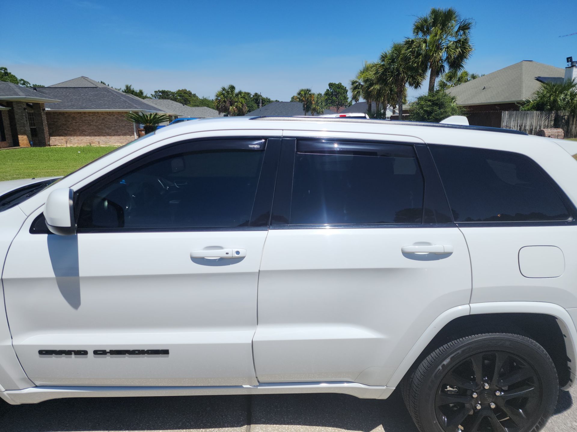 the image shows a white suv with window tinting on the side windows the service provided by the window tinting company likely involves applying a thin laminate film to the vehicle's glass this enhances privacy and reduces glare heat and uv ray exposure from the sun the appearance of the tint is smooth and professional indicating a quality installation service by t's window tinting in pensacola fl the car model is a jeep grand cherokee and the tint appears to be consistent across all the side windows providing a uniform look