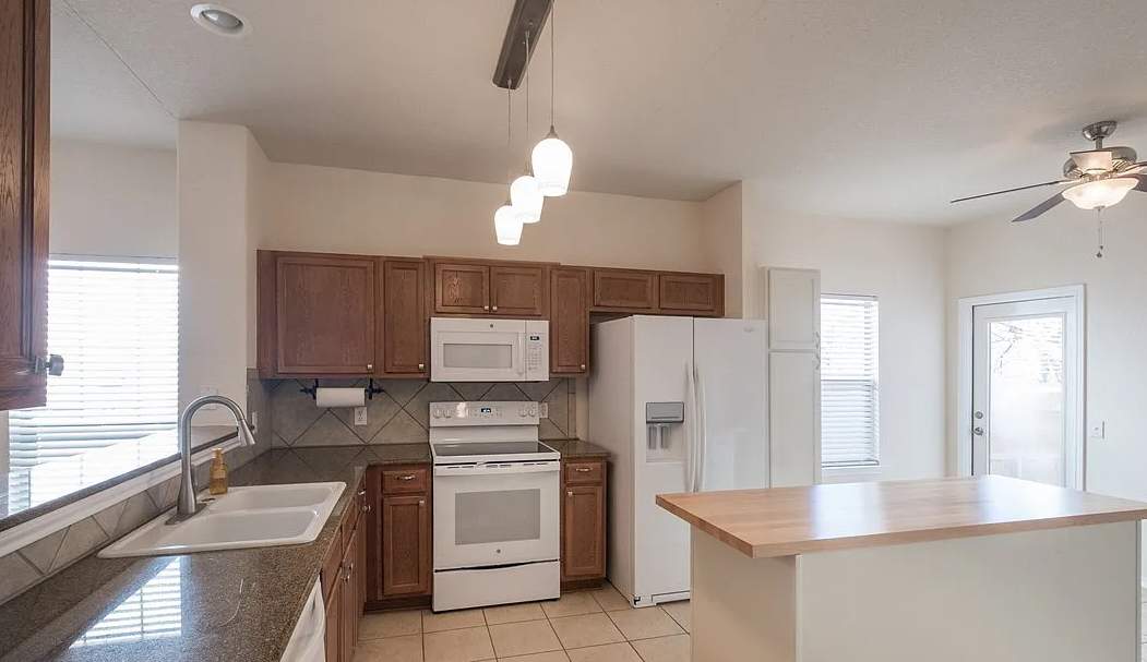 The old kitchen had a traditional builder-grade look with heavier wood cabinetry and busier finishes, while the new kitchen has a warm transitional design with cleaner lines, a brighter palette, and a more open, modern layout by Mena stone surfaces