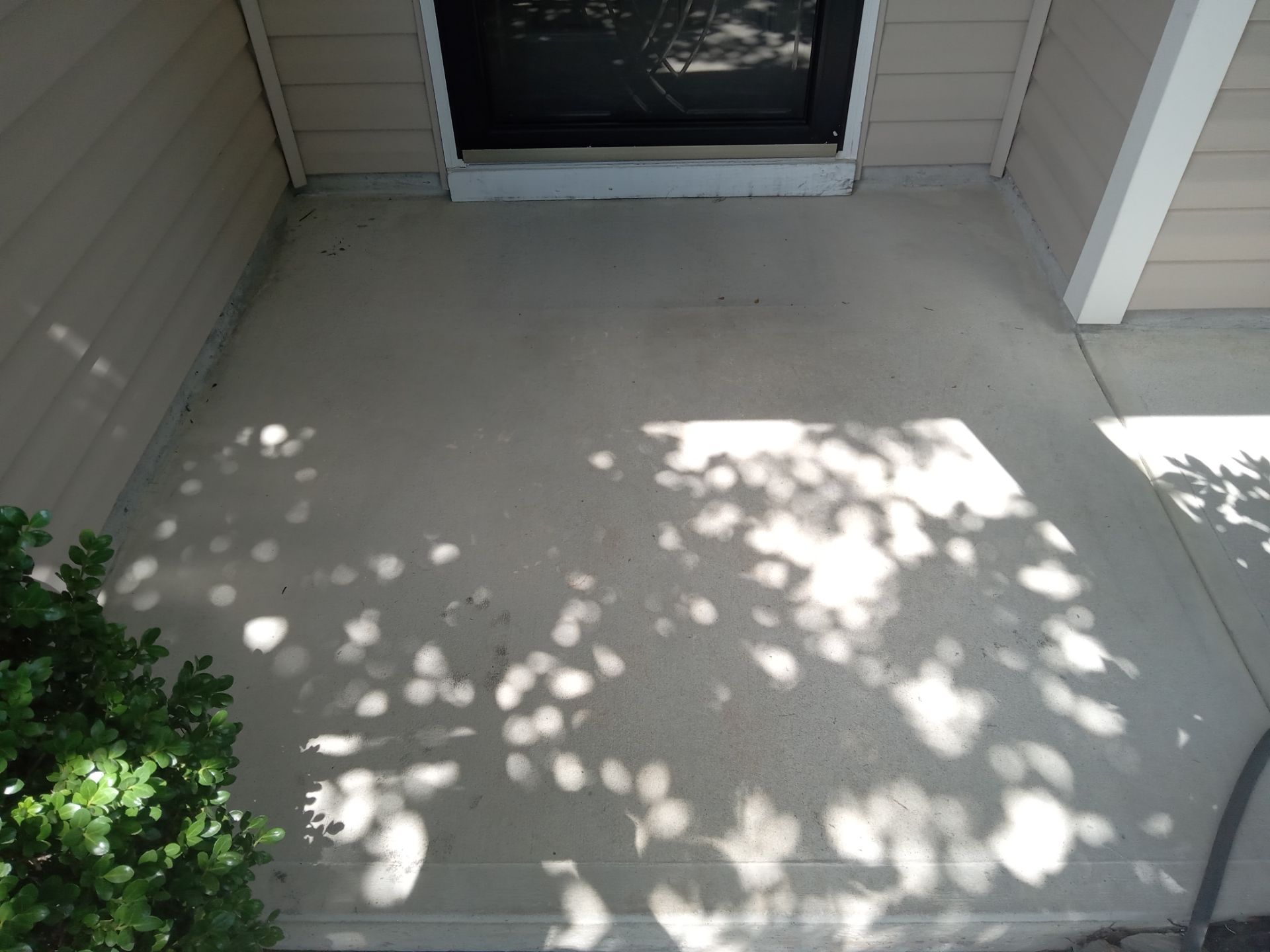 the photo shows a concrete surface likely a porch or a walkway leading to the entrance of a building the pressure washing company is cleaning the concrete removing dirt grime and possibly mildew or mold buildup to restore the surface to a cleaner state the difference in color between the cleaned and yet-to-be-cleaned areas indicates the effectiveness of the pressure washing service