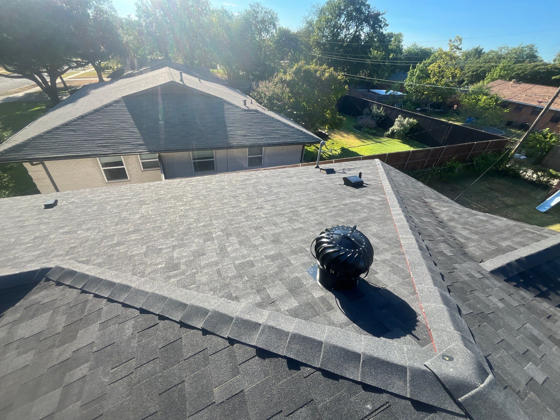 White brick/light gray shutters with IKO Granite Black  by Tejas Roofworks + Restoration