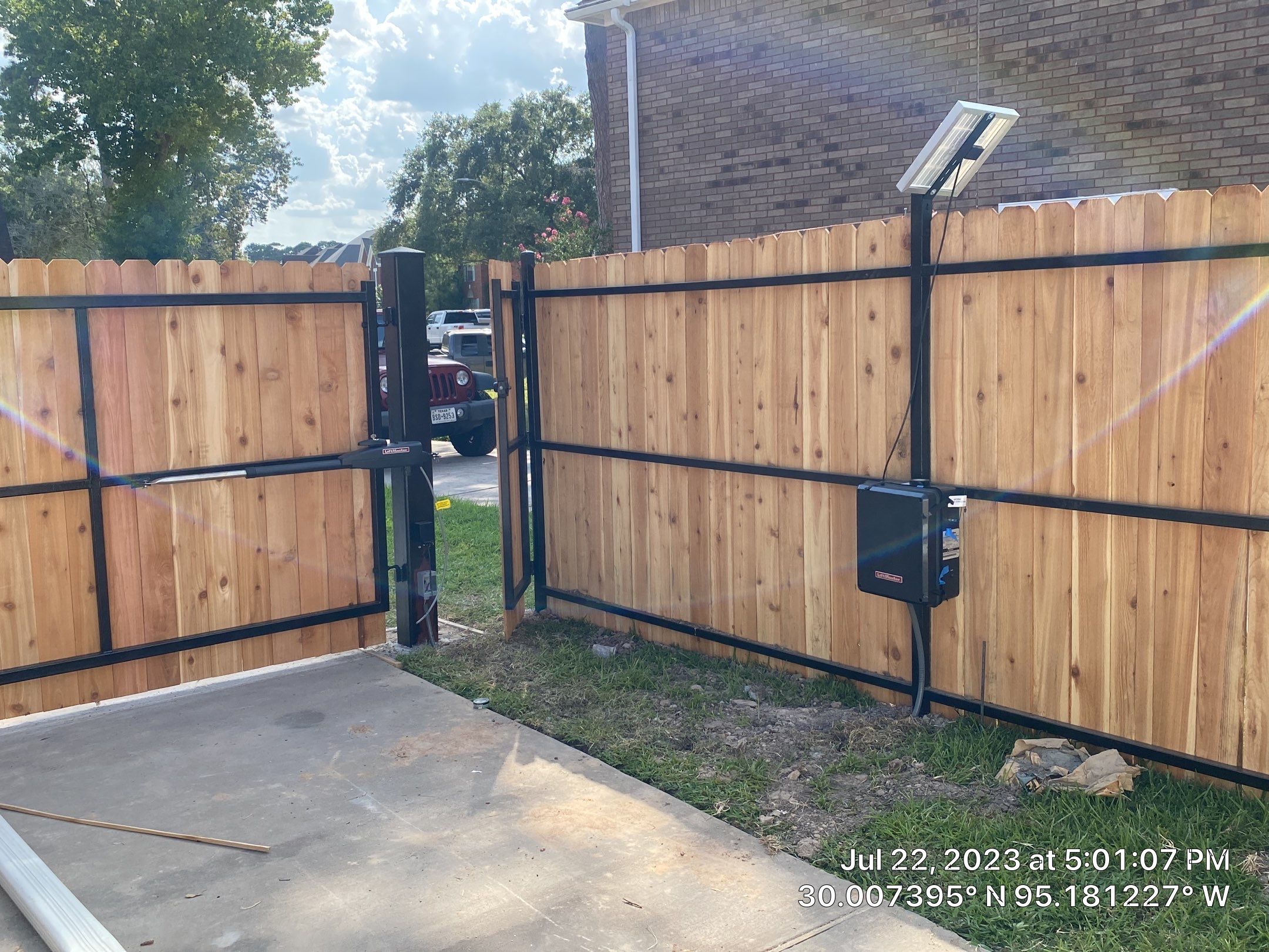 Complete metal driveway gate install with solar powered opener. Metal fence frame with Cedar Pickets by Astro Outdoor Designs 