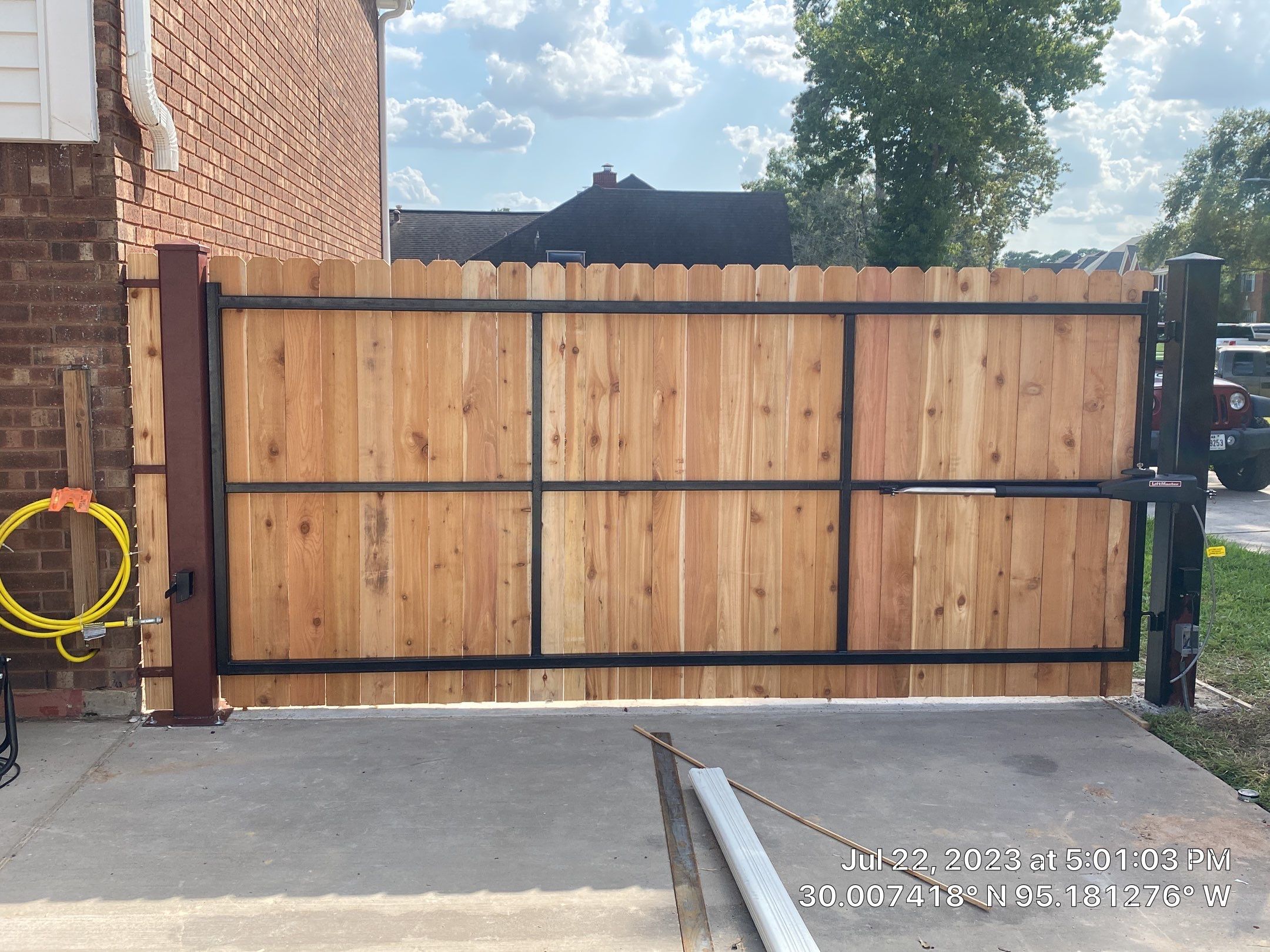 Complete metal driveway gate install with solar powered opener. Metal fence frame with Cedar Pickets by Astro Outdoor Designs 