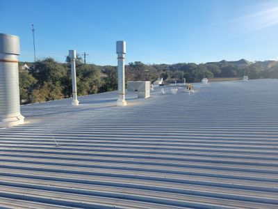 Metal roof with multiple ventilation pipes and clear sky