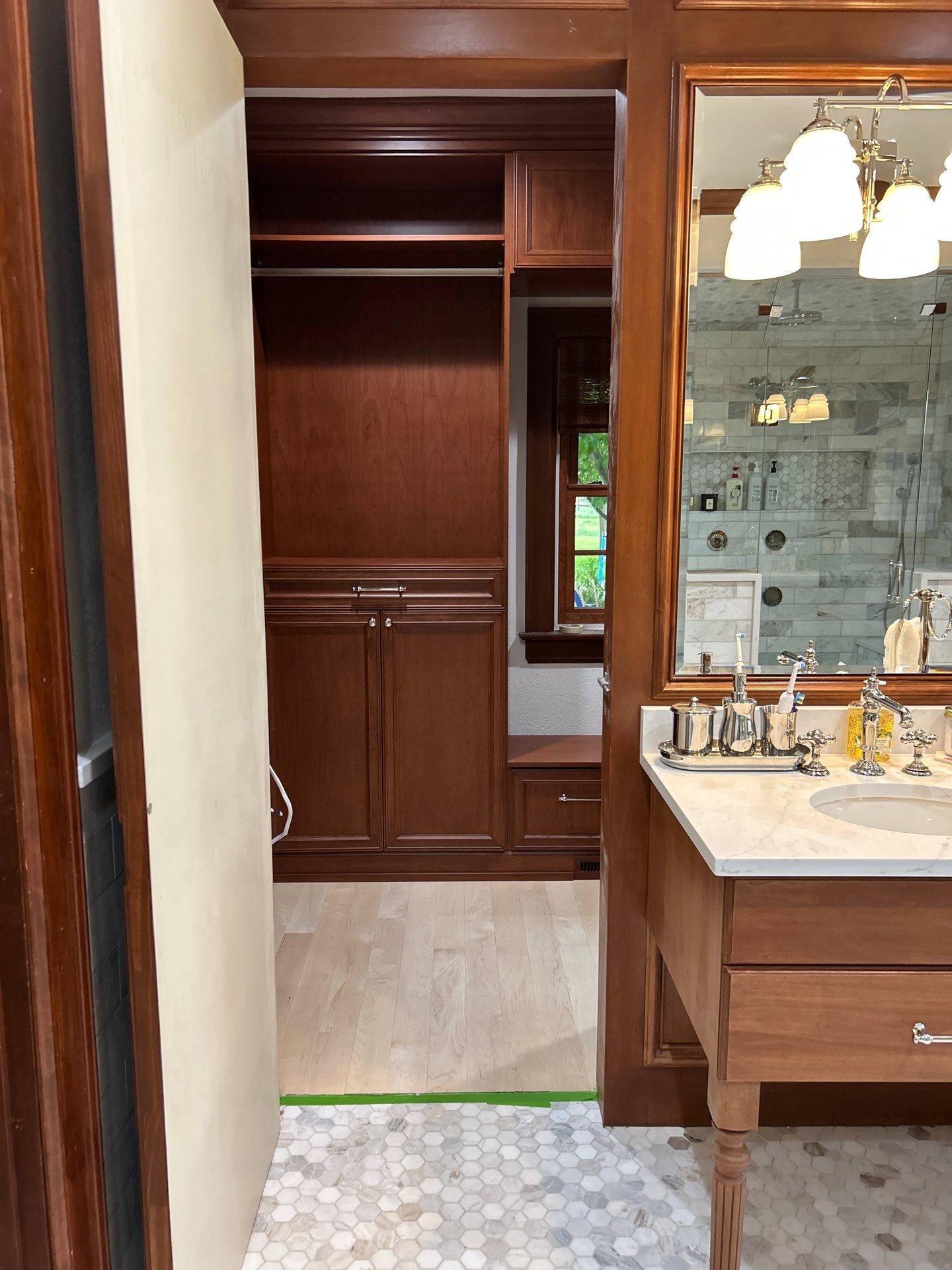 Stained Cherry Wood Primary Closet by Concept 32, Inc.