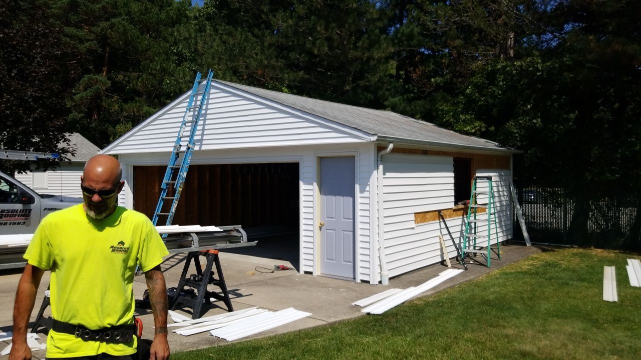 Siding Installation using Norandex woodsman dl-5 white woodgrain vinyl by Absolute Roofing and Construction