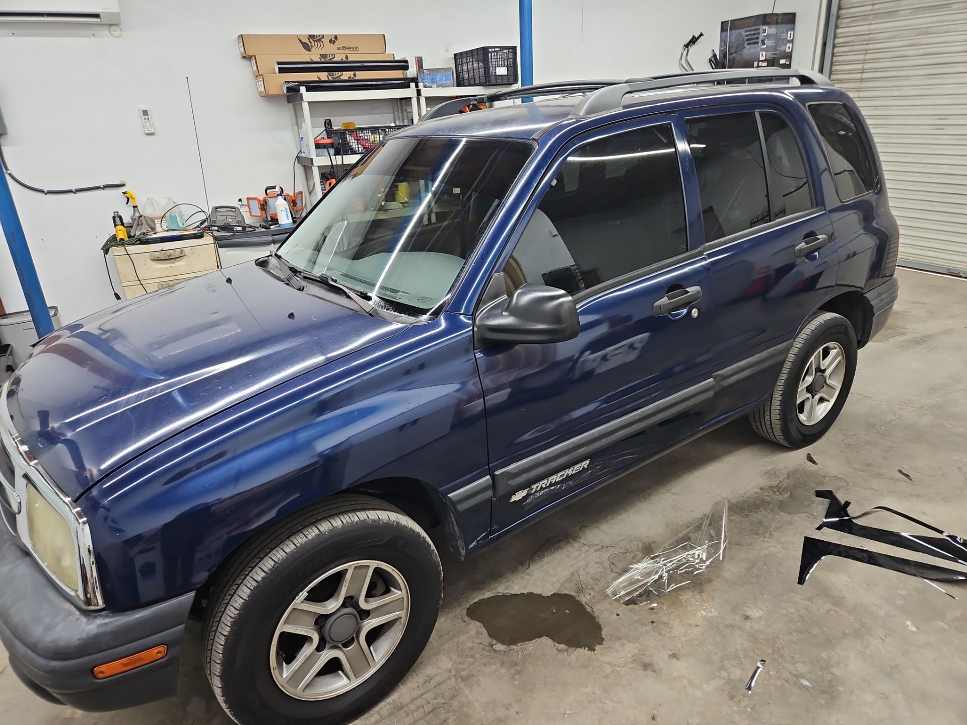 the image shows a car being prepared for window tinting service the vehicle is a blue suv which is likely undergoing the application of tinted film to its windows the process involves cleaning the windows before the tint is applied to ensure proper adhesion the shop appears to be organized with tools and materials nearby ready for the tint installation the attention to detail indicates a professional approach to the window tinting service being provided