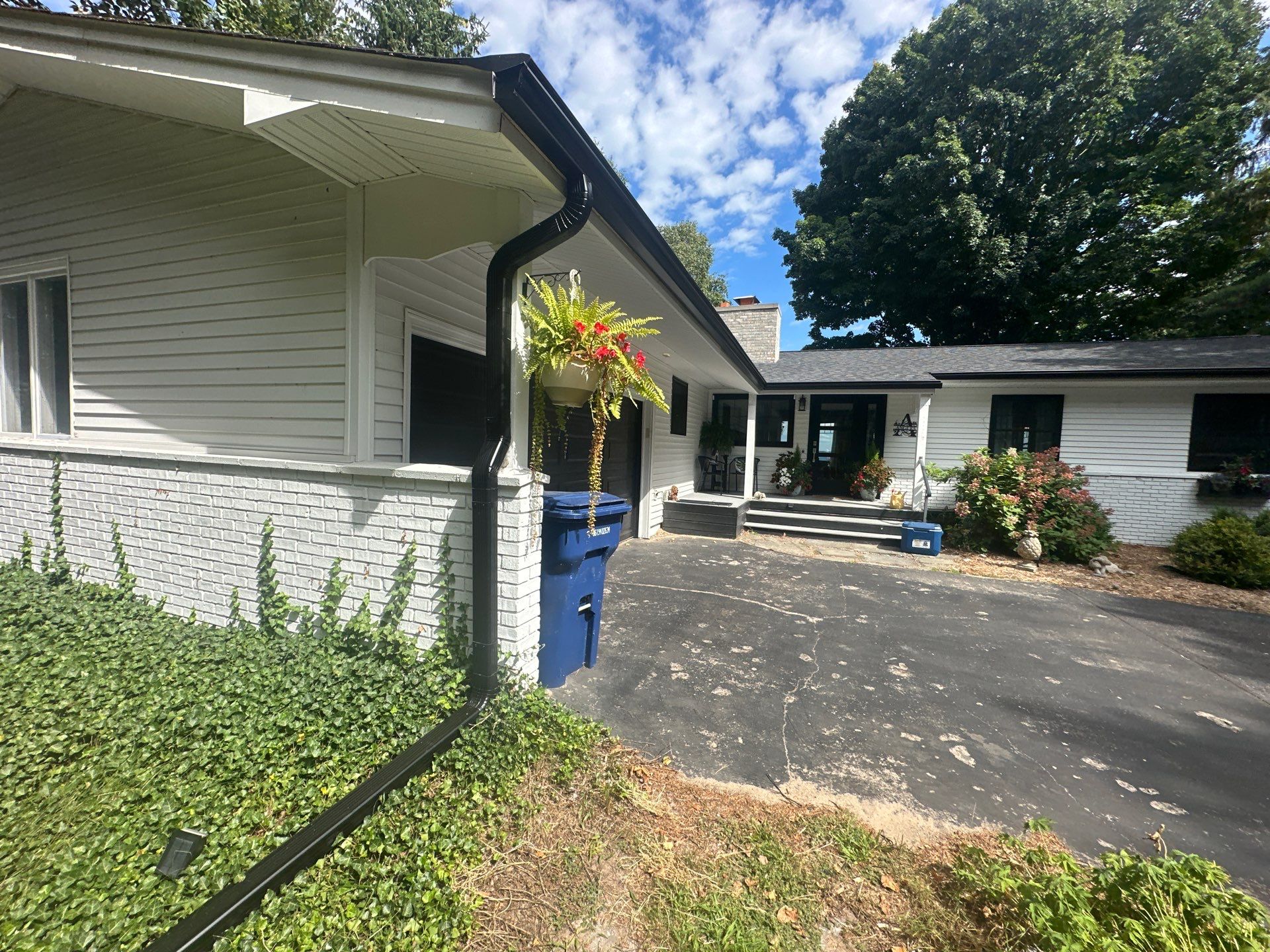 Black Gutter and Gutter Helmet Installation for Suttons Bay Home by Rainbow Seamless Systems