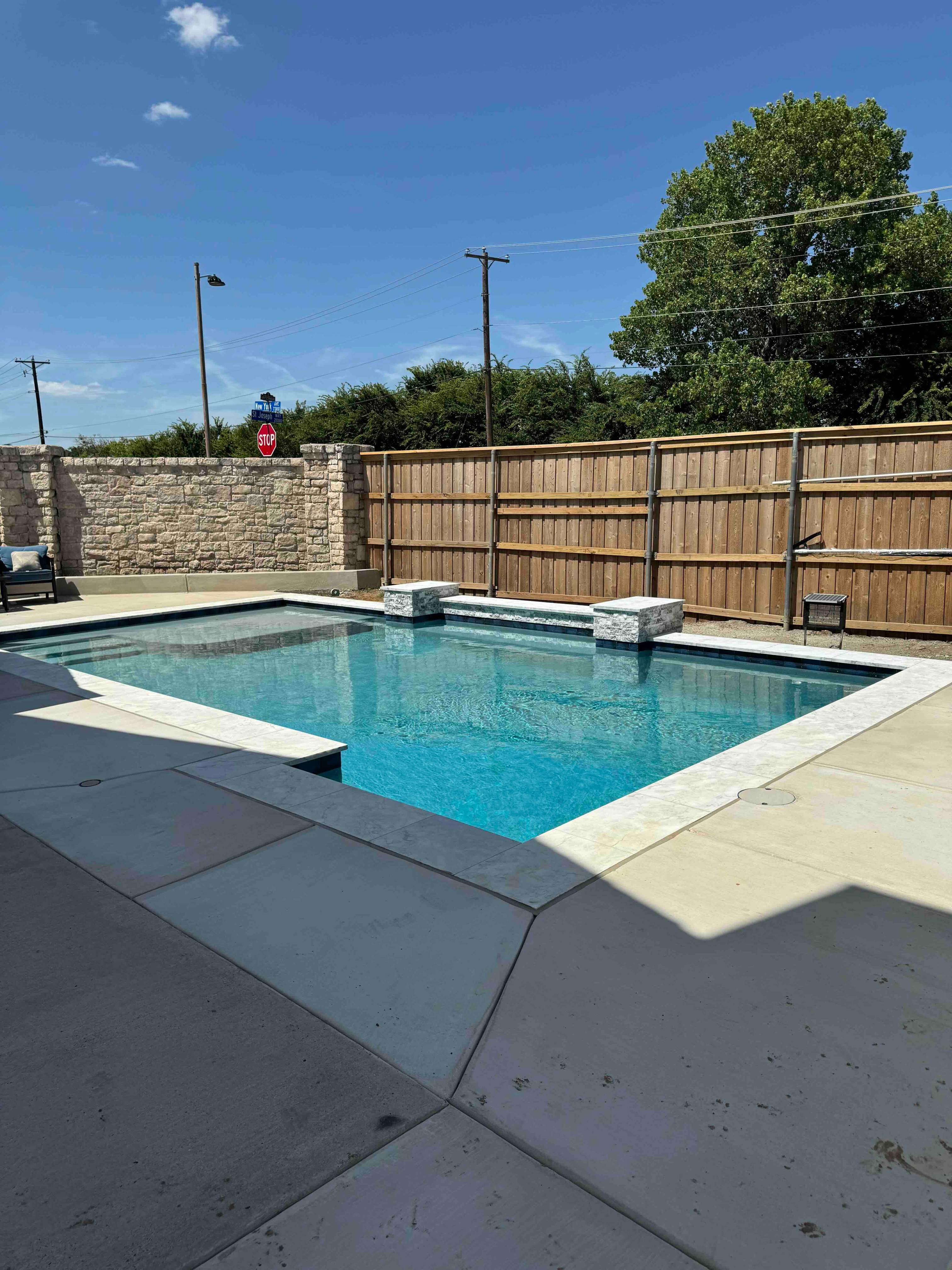 Geometric Pool with Raised Stone Accent Wall by Pinnacle Pools and Spas - DFW