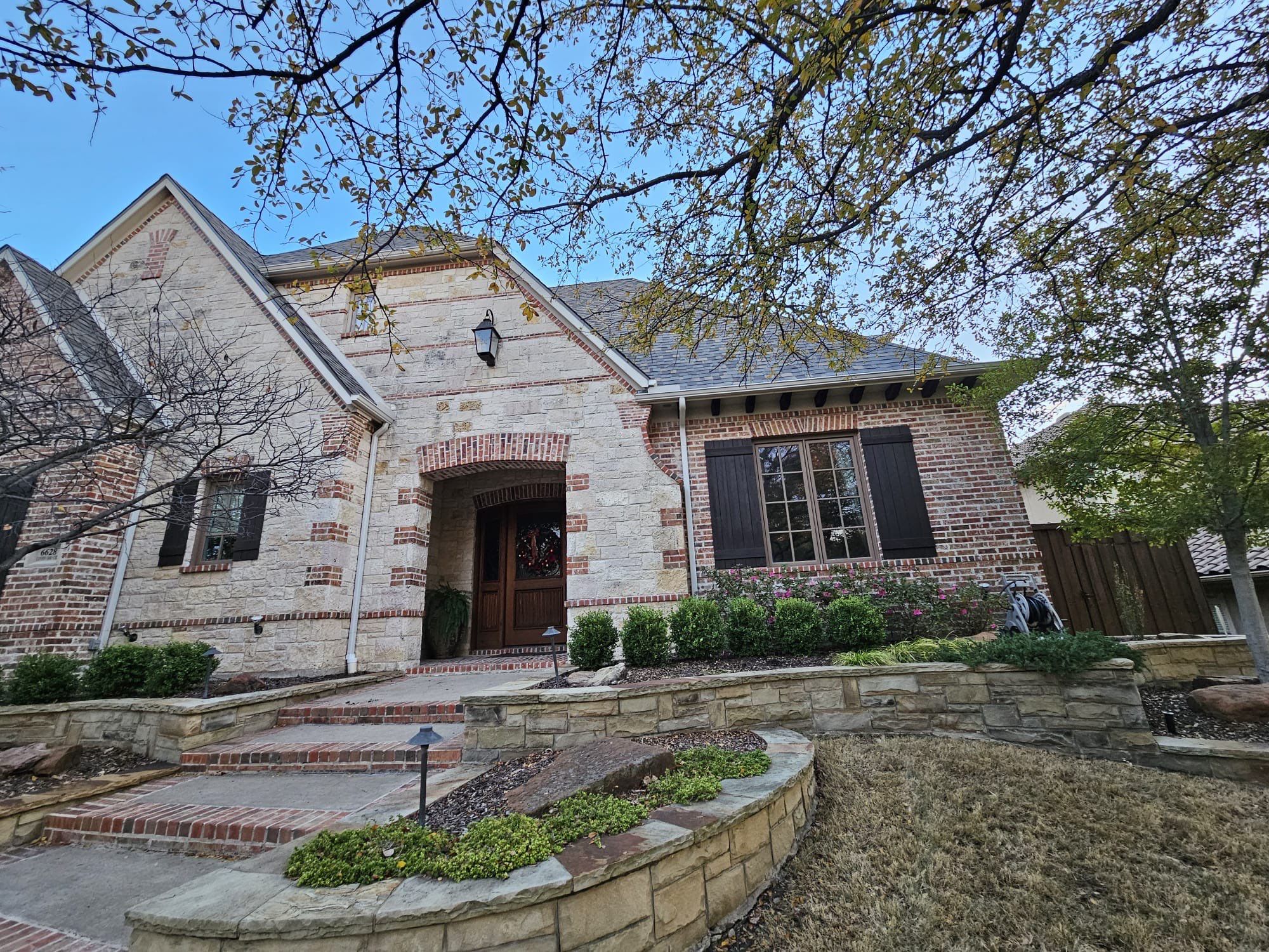 Light red brick/cream stone/espresso shutters with IKO Cornerstone by Tejas Roofworks + Restoration