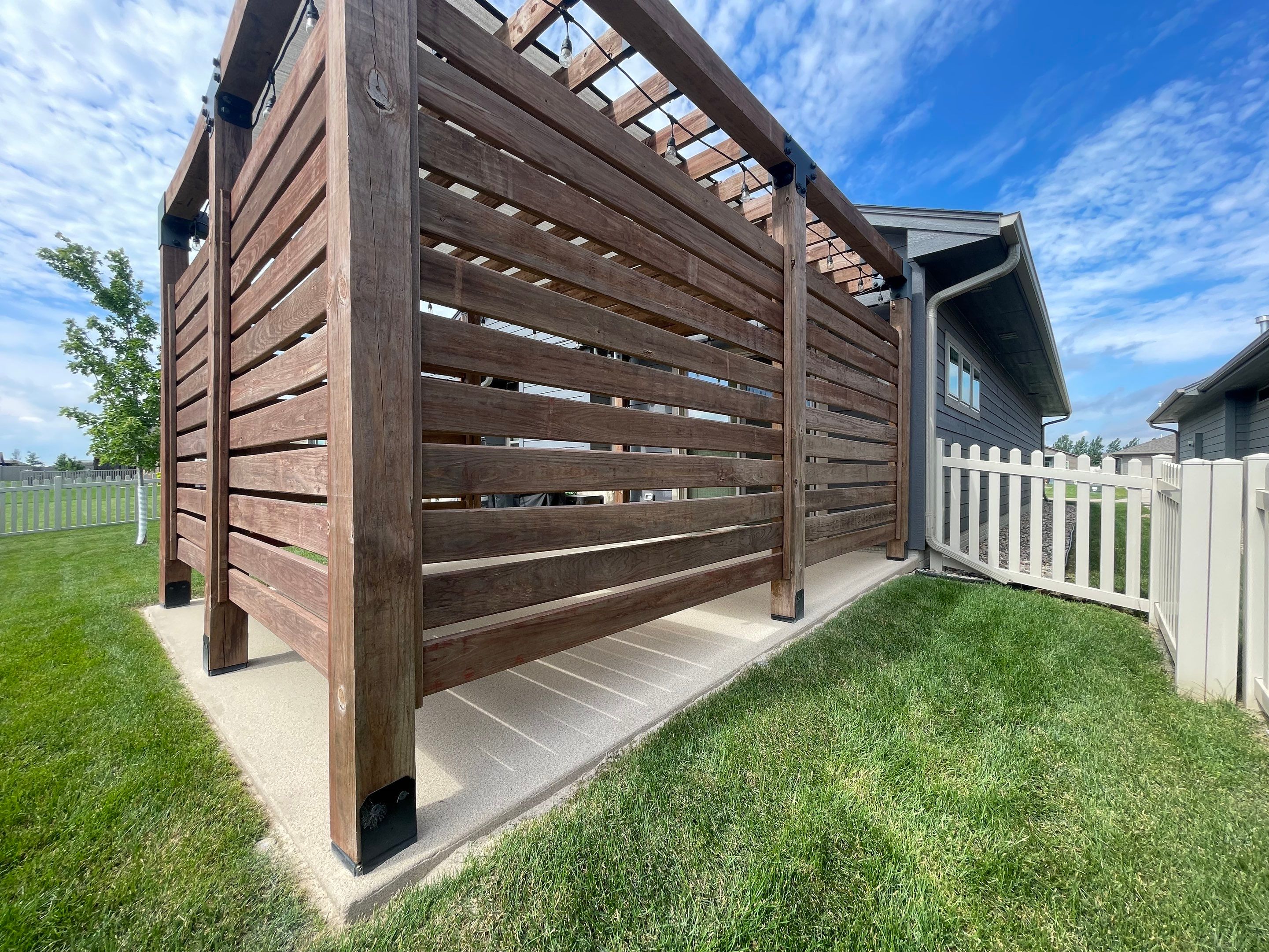 Textured Concrete Patio Coating and Custom Privacy Pergola in Sioux Falls by Select Painting, Coatings & Garage Cabinets