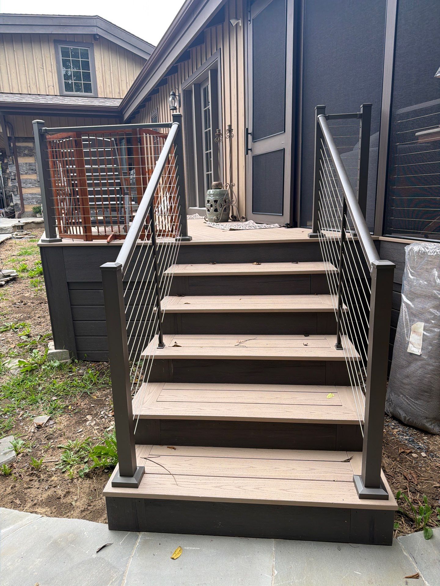 Custom Composite Deck with Stone Fireplace and Modern Cable Railing by Walnut Hollow Decks & Outdoor Living