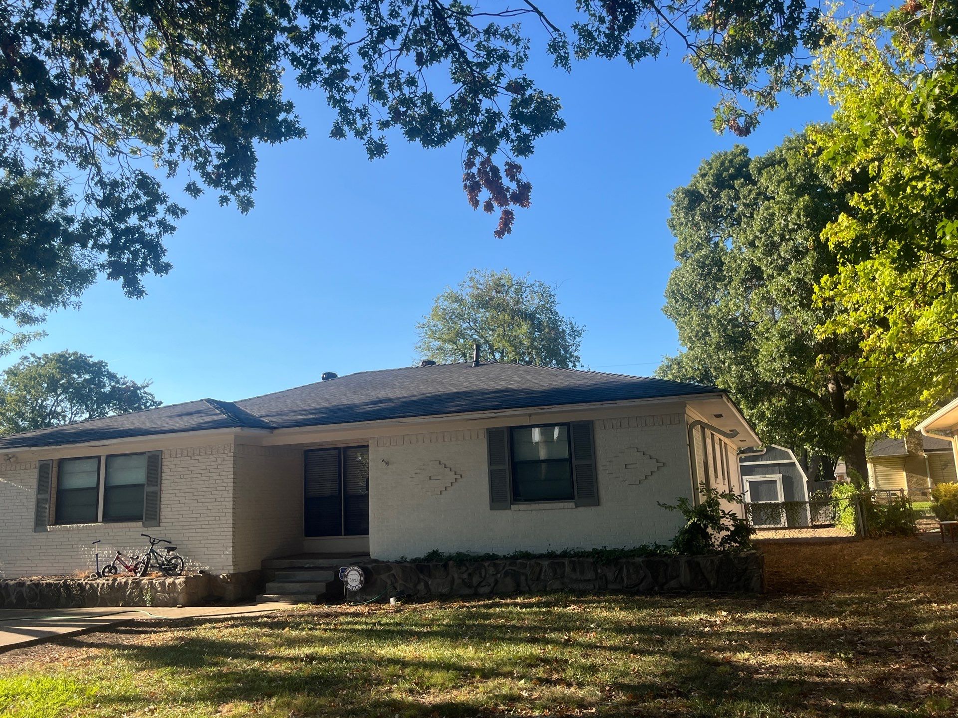White brick/light gray shutters with IKO Granite Black  by Tejas Roofworks + Restoration