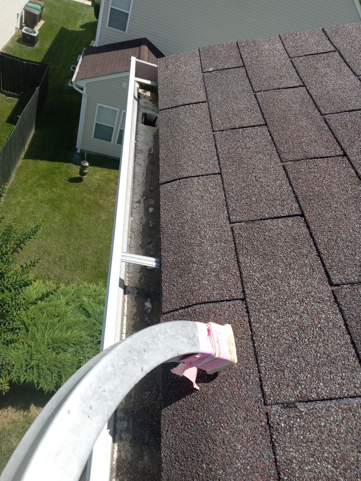 in this photo a pressure washing company is cleaning a home's gutter system the gutters appear to have accumulated dirt leaves and debris which is common over time they are using a cleaning method to remove this buildup from the inner surface of the gutters to ensure proper water flow and to maintain the home's exterior cleanliness it appears that the cleaning process may involve high-pressure water or specialized tools to dislodge and remove the gutter debris typically such services would include flushing the gutters and downspouts to ensure they are fully clear and functional