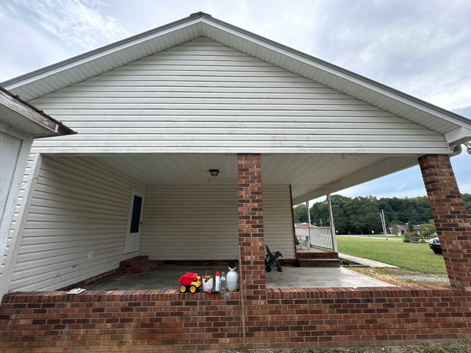 pressure washing is being done on the porch siding and brick surfaces to remove dirt and grime