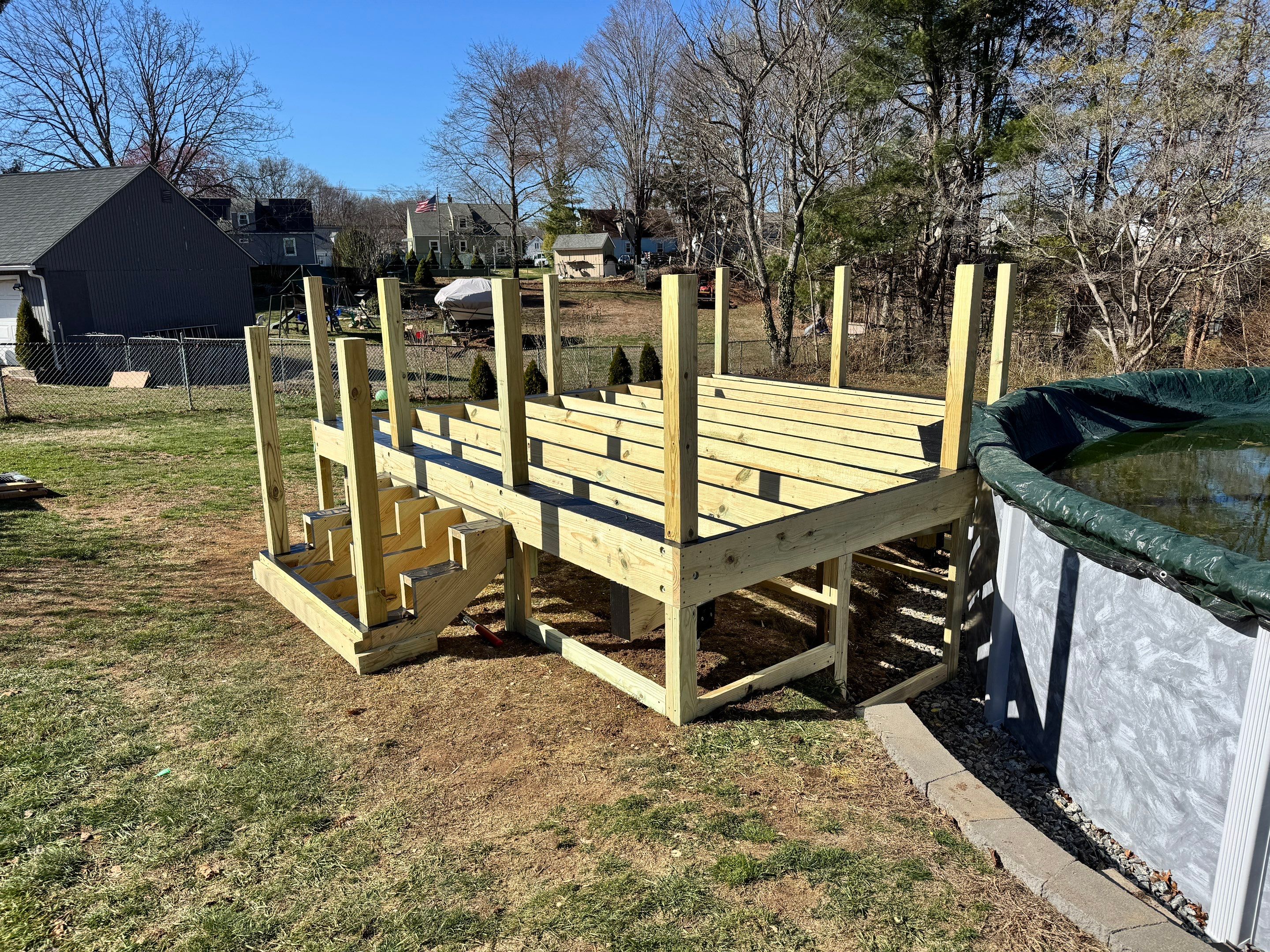 New pool deck using Trex Pebble Gray boards and White composite railings and lattice  by DiGiorgi Roofing and Siding Inc