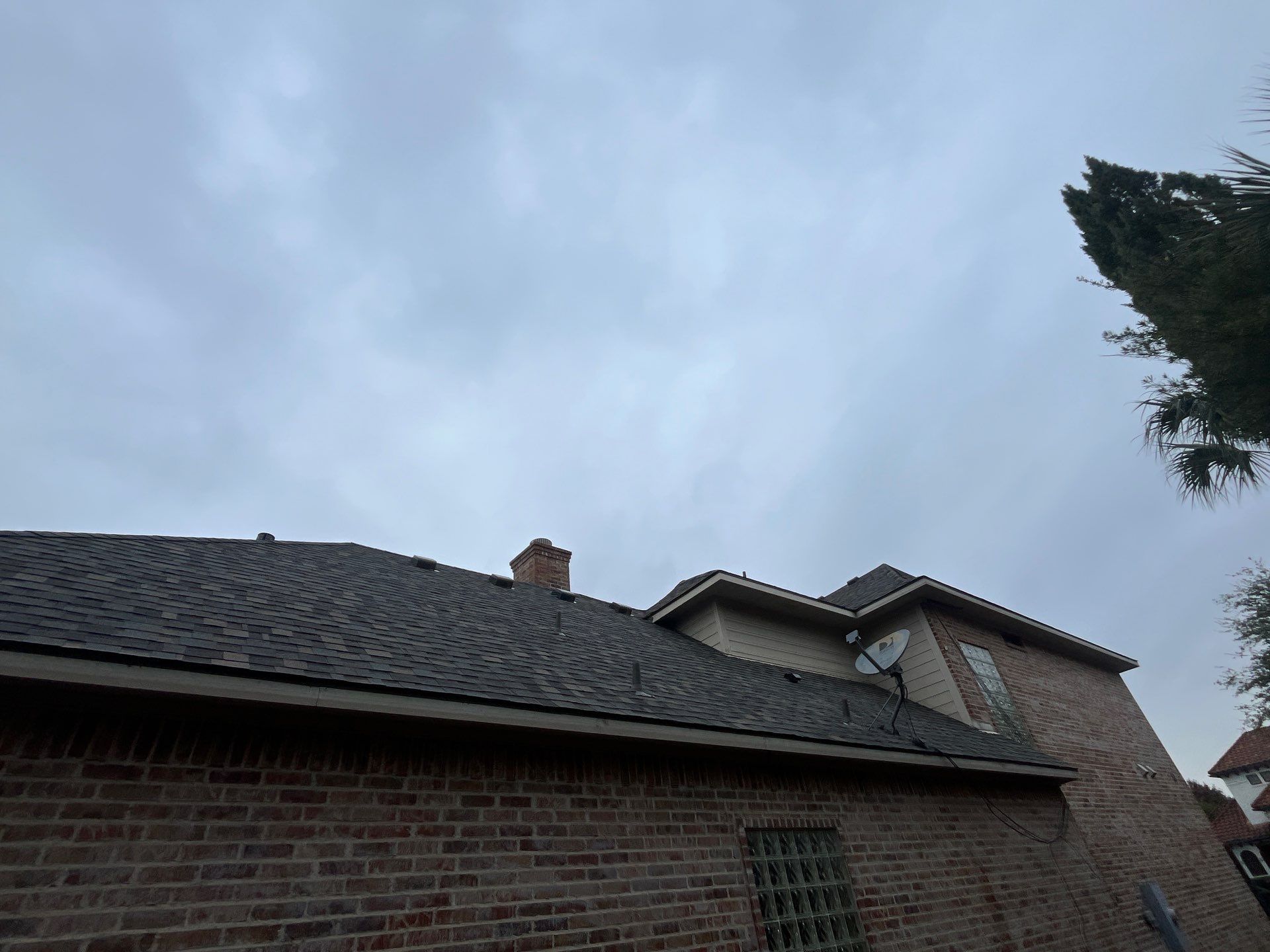 Light red brick/cream stone/espresso shutters with IKO Cornerstone by Tejas Roofworks + Restoration