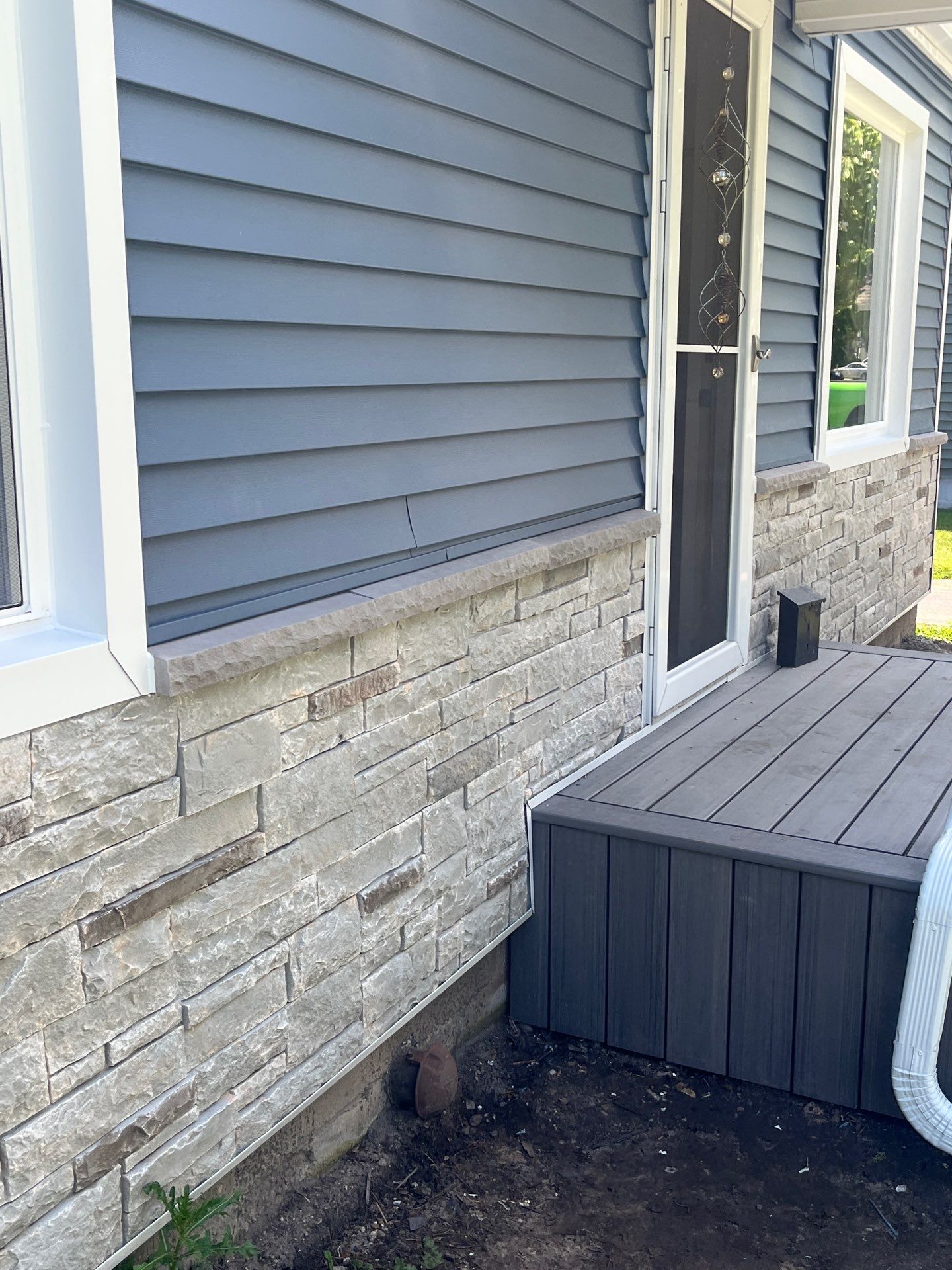 Blue Vinyl Siding and Versetta Stone Exterior Remodel in Bay City by Great Lakes Home Design LLC