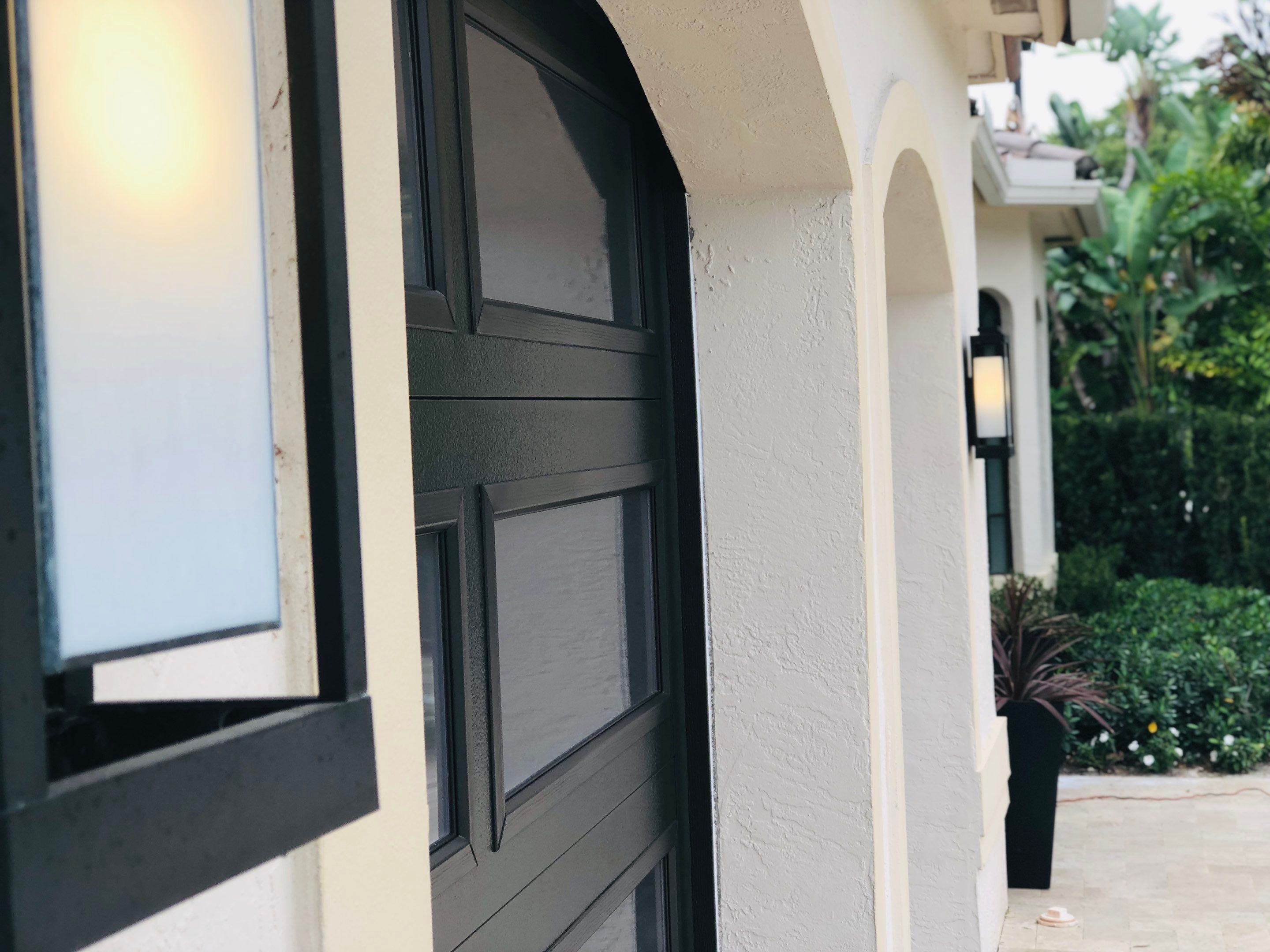 Modern Bronze Garage Door Installation With Frosted Glass in Boca Raton by The Door Doctor of South Florida, Inc.