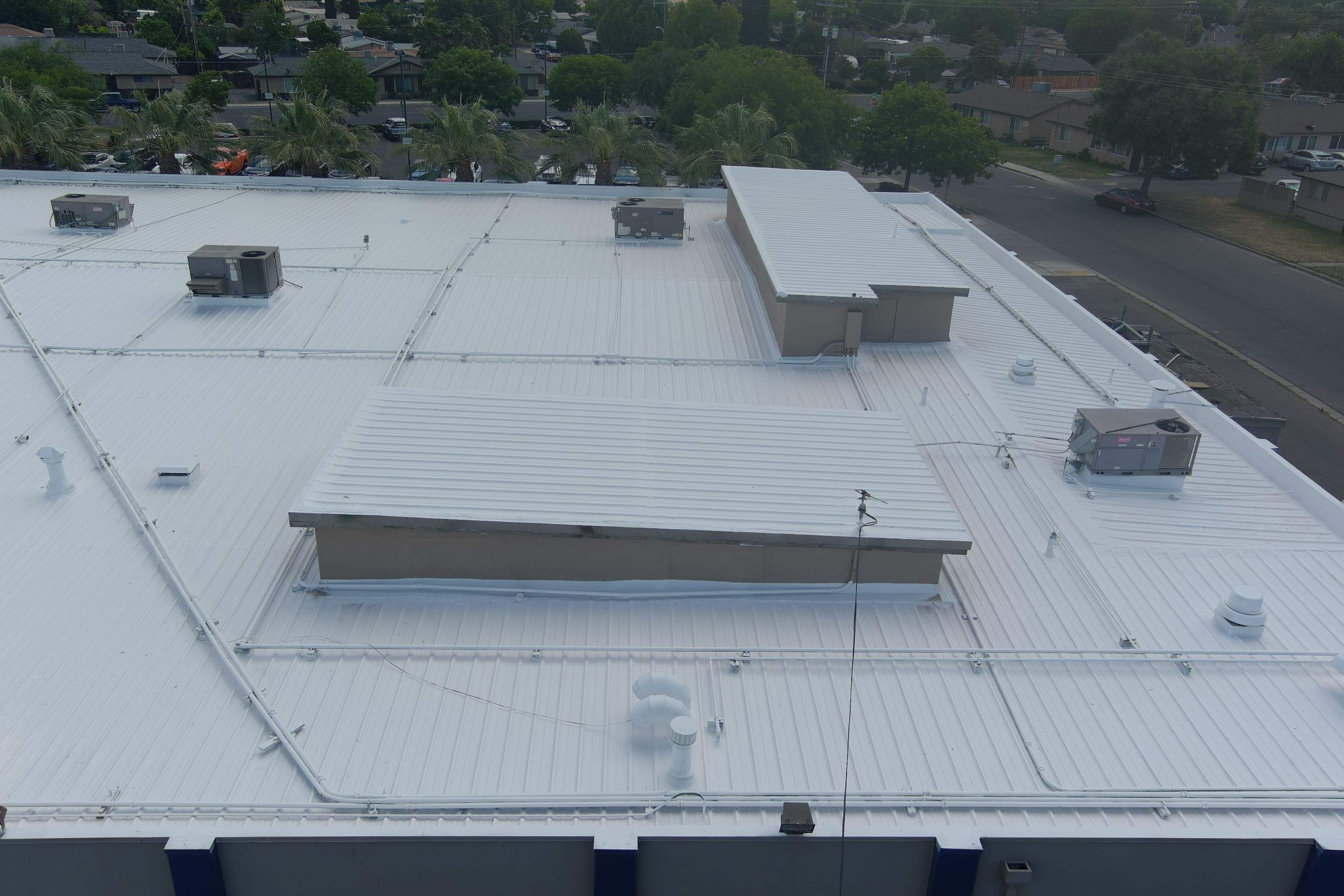 Metal roof restoration on commercial roof using Conklin Benchmark/ PUMA XL acrylic coatings over metal and foam by Straight Edge Roofing Inc