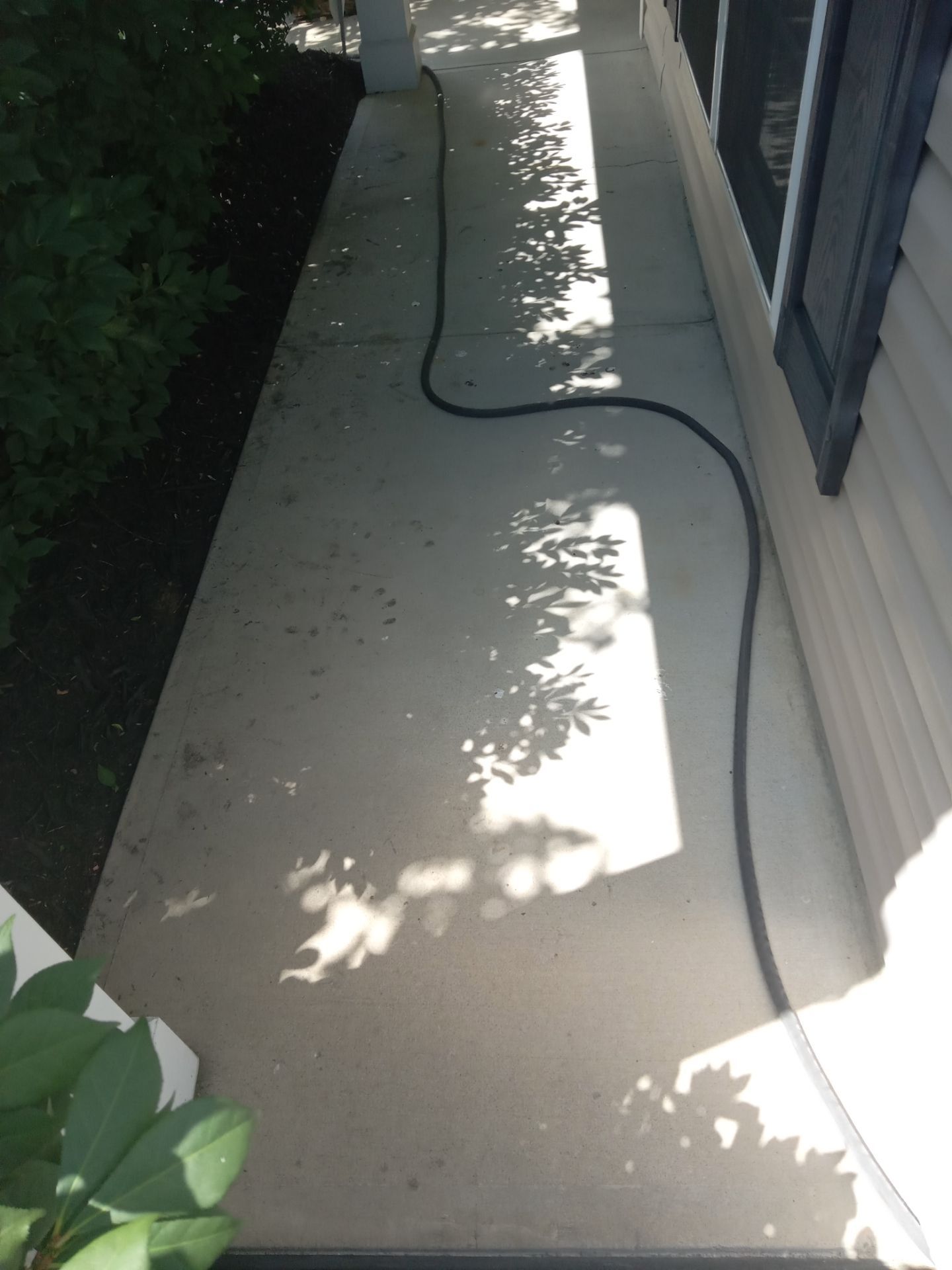 in the photo a pressure washing company is cleaning a concrete walkway the image shows a clear demarcation where the pressure washing has removed dirt and grime on one side making the concrete noticeably cleaner compared to the other side which remains dirty and stained the service effectively restores the walkway's appearance by removing layers of accumulated dirt