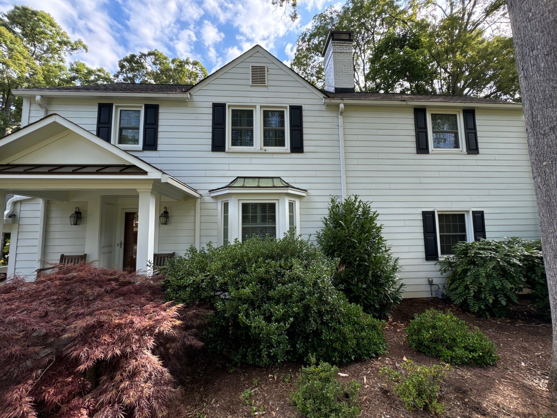 pressure washing the exterior siding of a two-story house