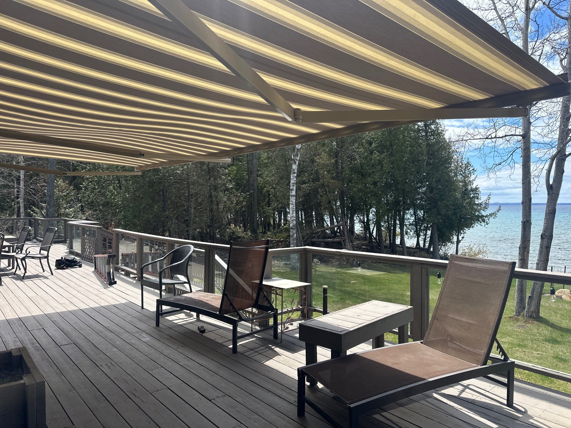 Retractable Striped Awning Installation for Waterfront Composite Deck in Charlevoix by Rainbow Seamless Systems