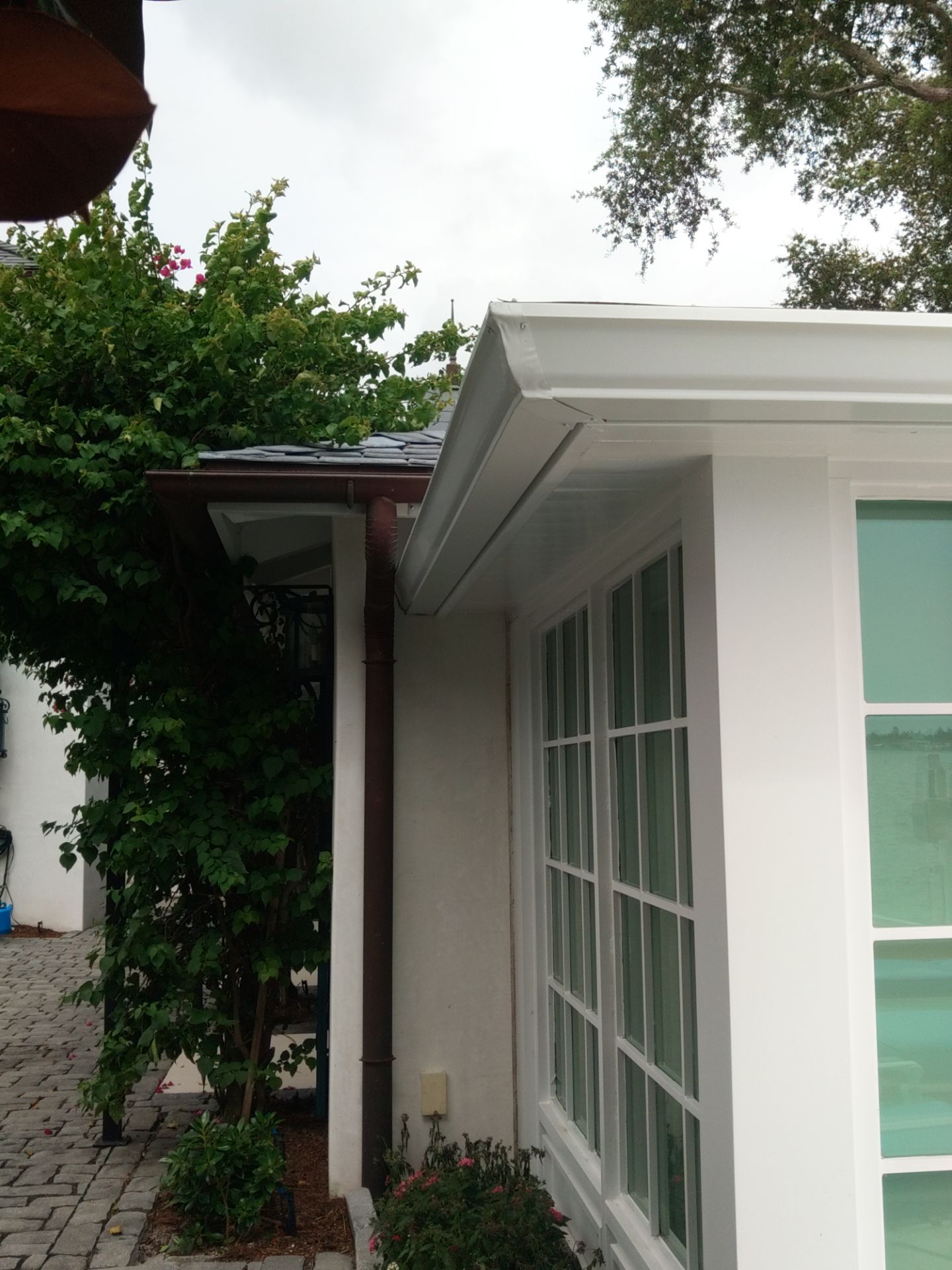 Seamless aluminum gutter installation in Sarasota, FL using 3x4 elbow downspouts combined with round downspouts by Gutter Professors