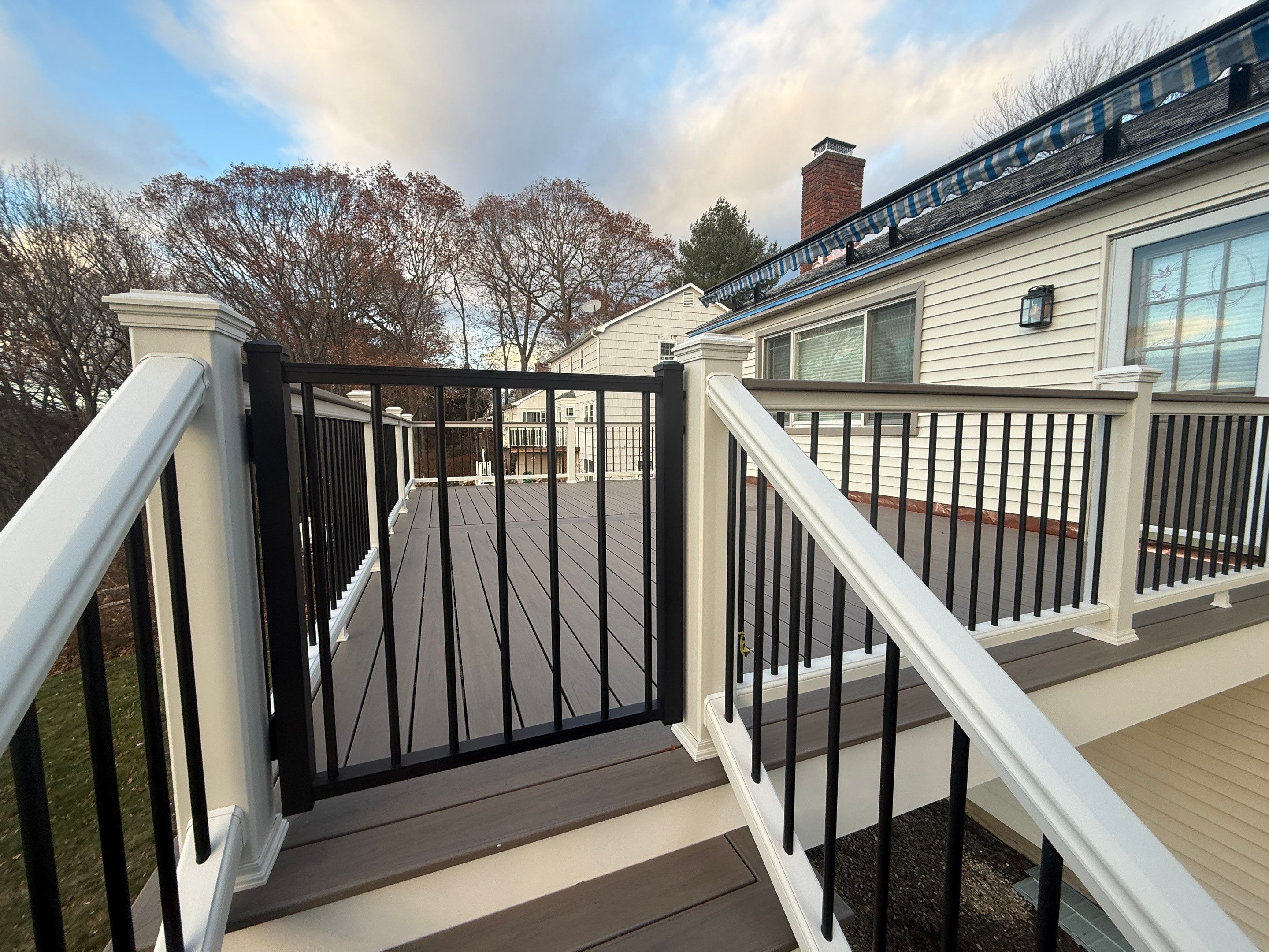 Replacement deck with Trex linage Biscayne boards and White Transcend railing with cocktail rail, and Trex gate. by DiGiorgi Roofing and Siding Inc