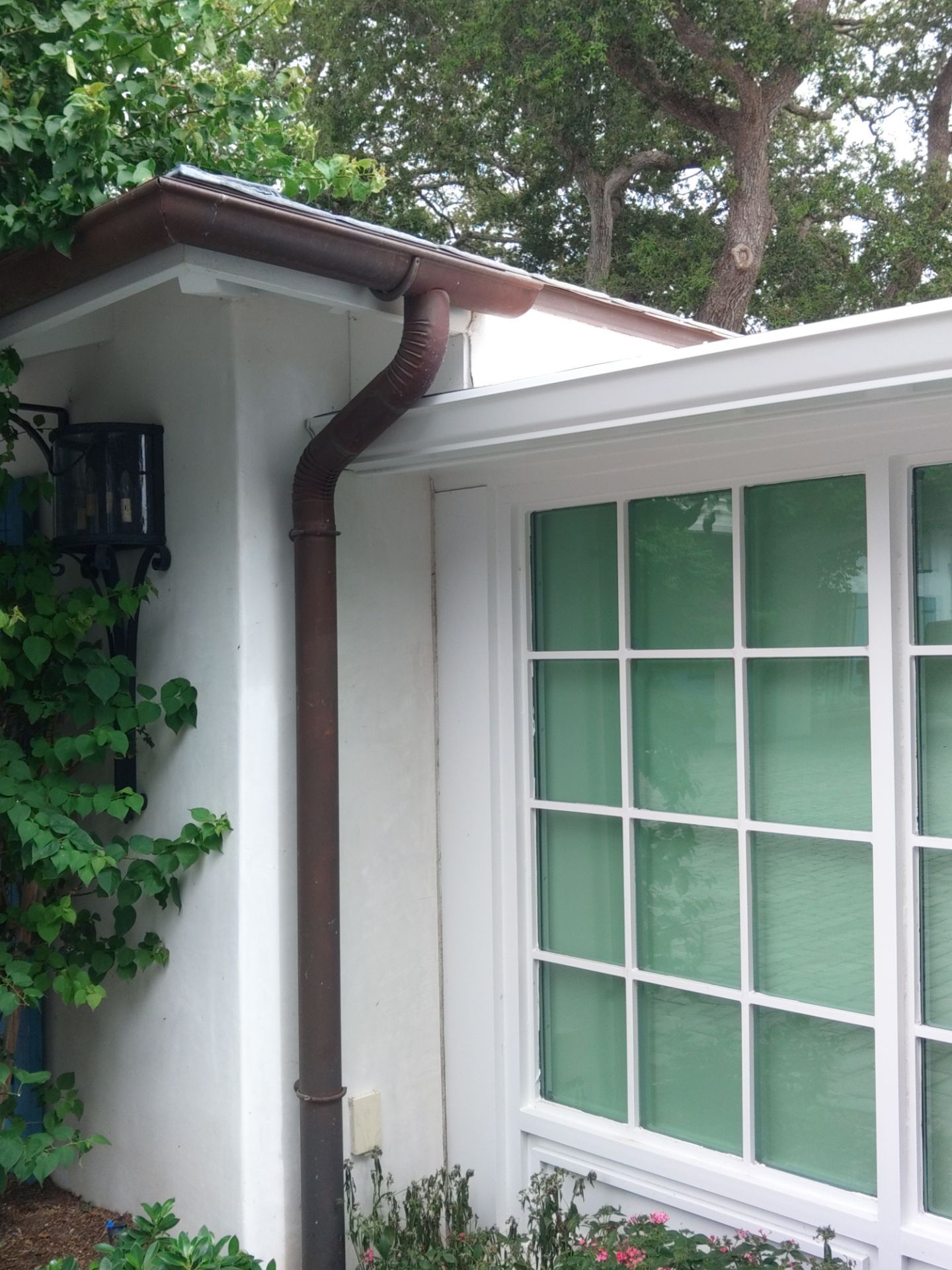 Seamless aluminum gutter installation in Sarasota, FL using 3x4 elbow downspouts combined with round downspouts by Gutter Professors