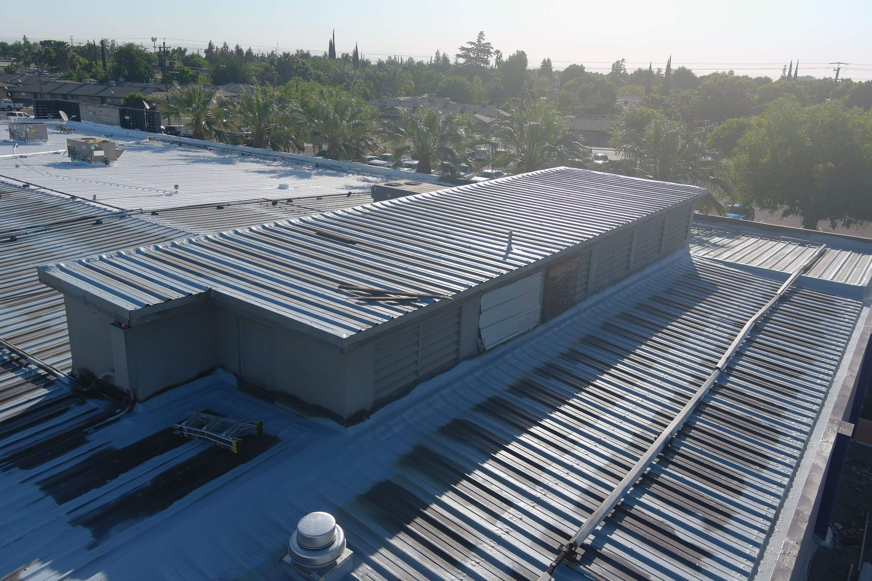 Metal roof restoration on commercial roof using Conklin Benchmark/ PUMA XL acrylic coatings over metal and foam by Straight Edge Roofing Inc