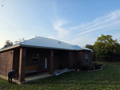 Completed metal roof on a brick home at sunset.