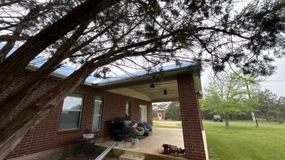 In-progress metal roof installation on a brick home exterior.