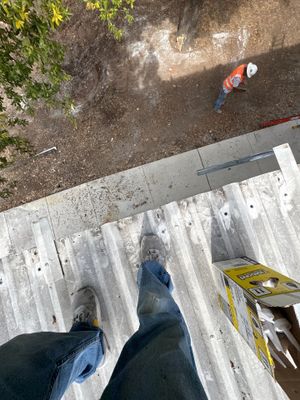 Worker standing on corrugated metal roof surface