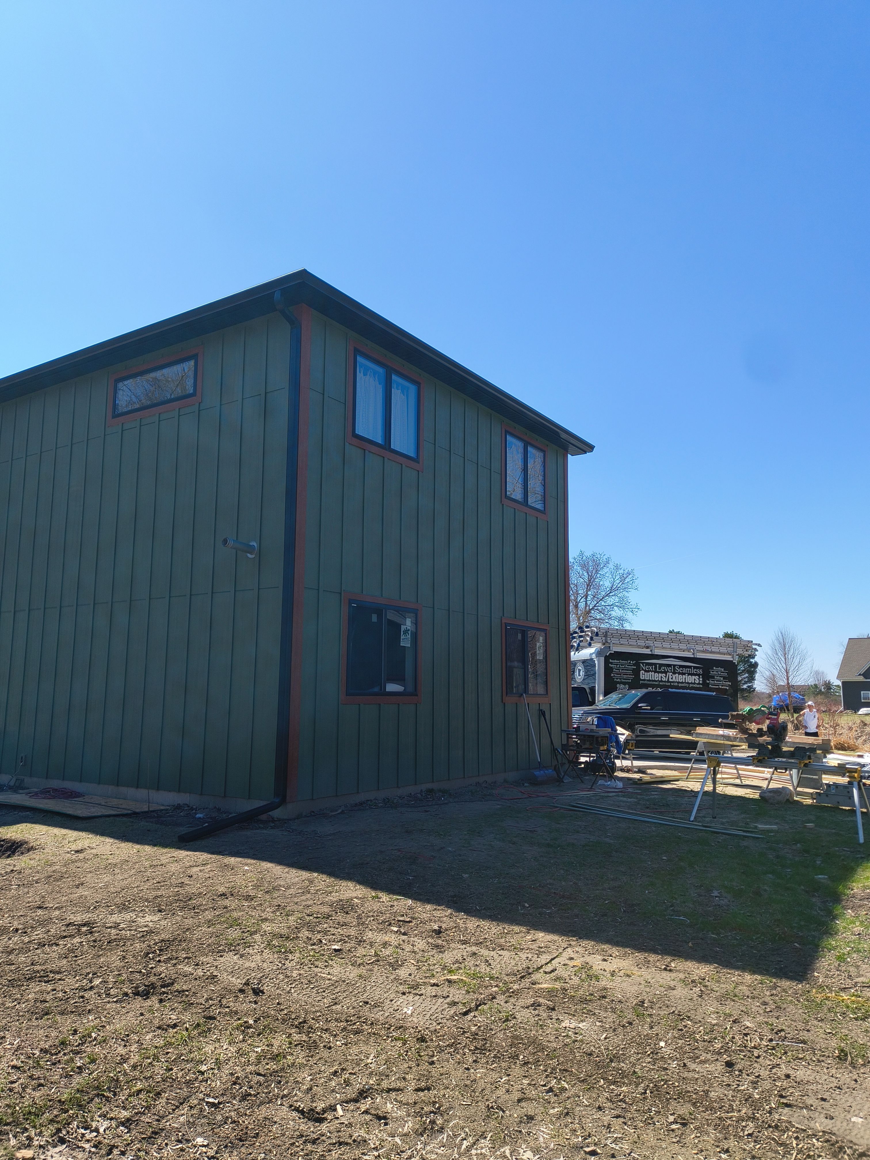 Seamless Gutter Installation in Annandale MN | 6” Black Gutters on Green Home by Next Level Seamless Gutters / Exteriors Inc.