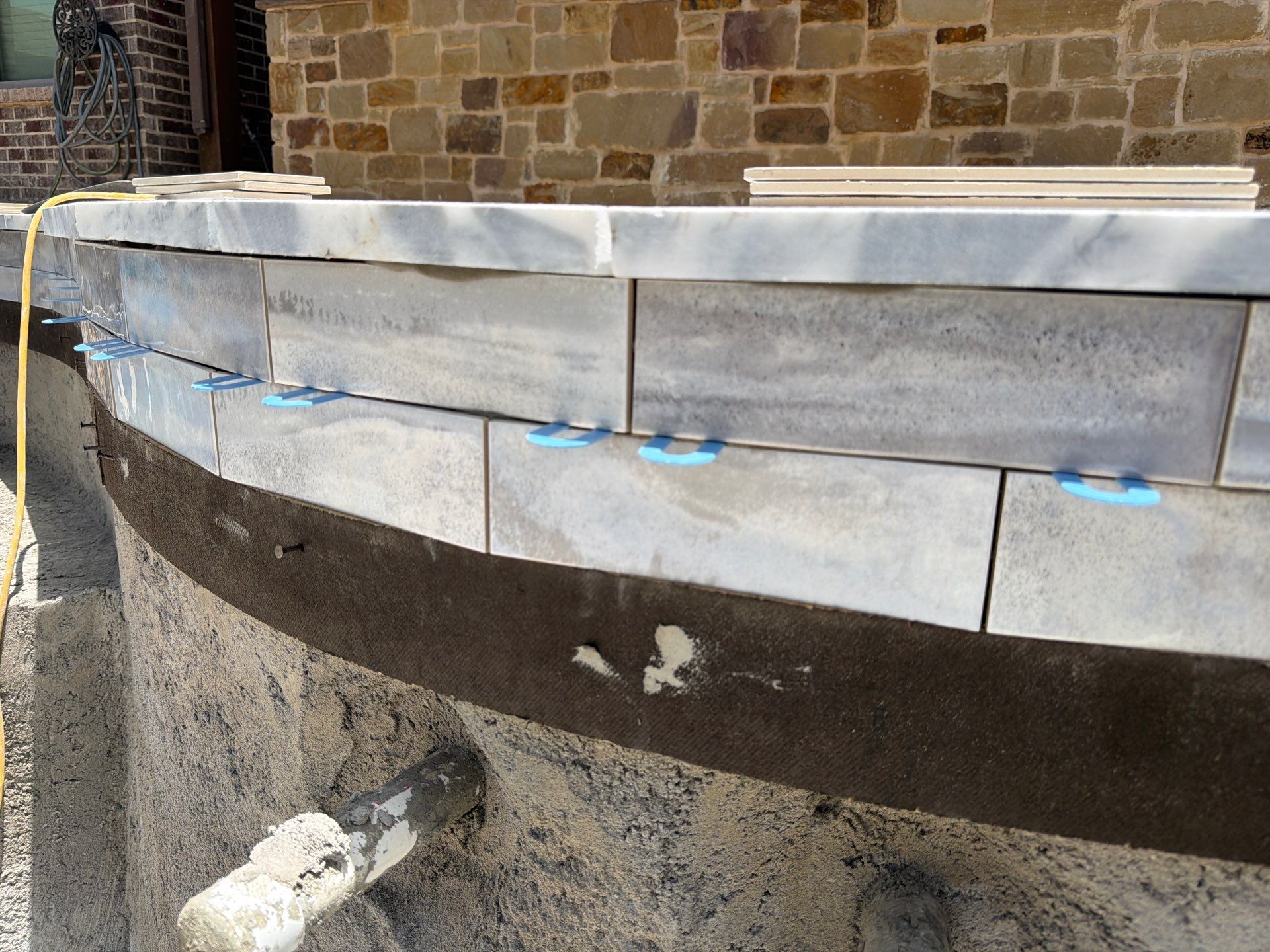 Freeform Pool with Tanning Ledge and Raised Stone Wall by Pinnacle Pools and Spas - DFW