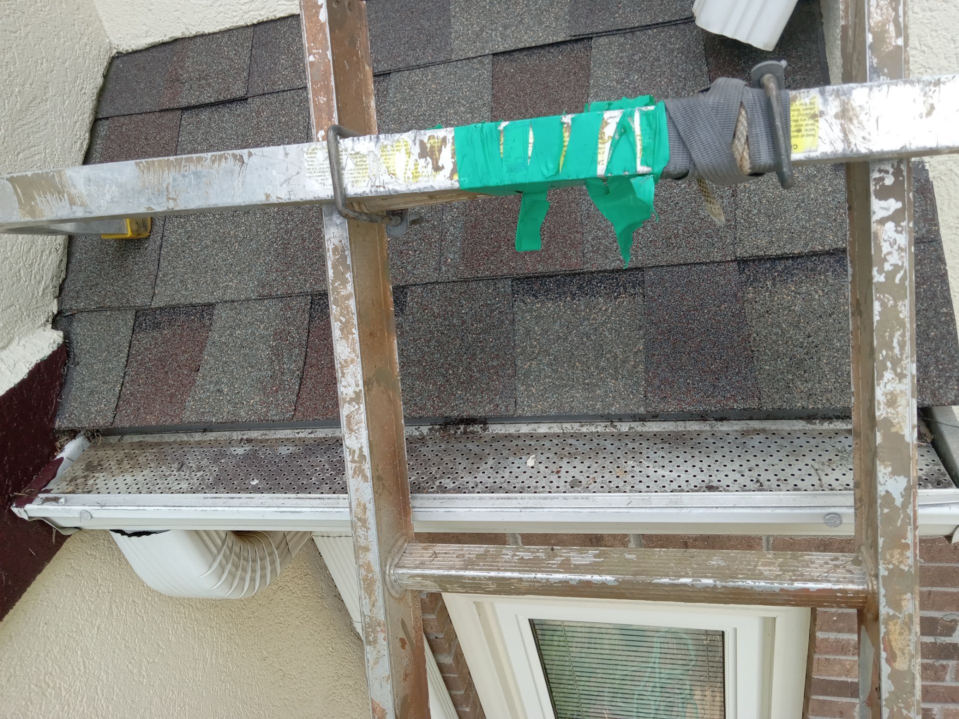 in the image there is a ladder leaning against a house where a gutter cleaning service is likely being performed the ladder provides access to the roof and gutter system typically a pressure washing company would remove debris like leaves twigs and dirt buildup to ensure proper water flow and to prevent blockages the gutters appear to have mesh guards which are designed to prevent larger objects from entering the gutters during the cleaning process water may be used to flush out smaller particles and ensure that the gutters are fully cleaned the surrounding areas such as the siding and window may also be cleaned to maintain the home's overall appearance