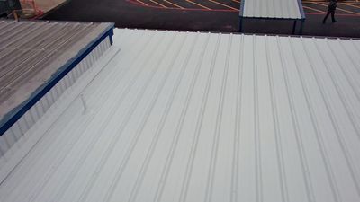 White flat roof membrane next to older weathered roof section