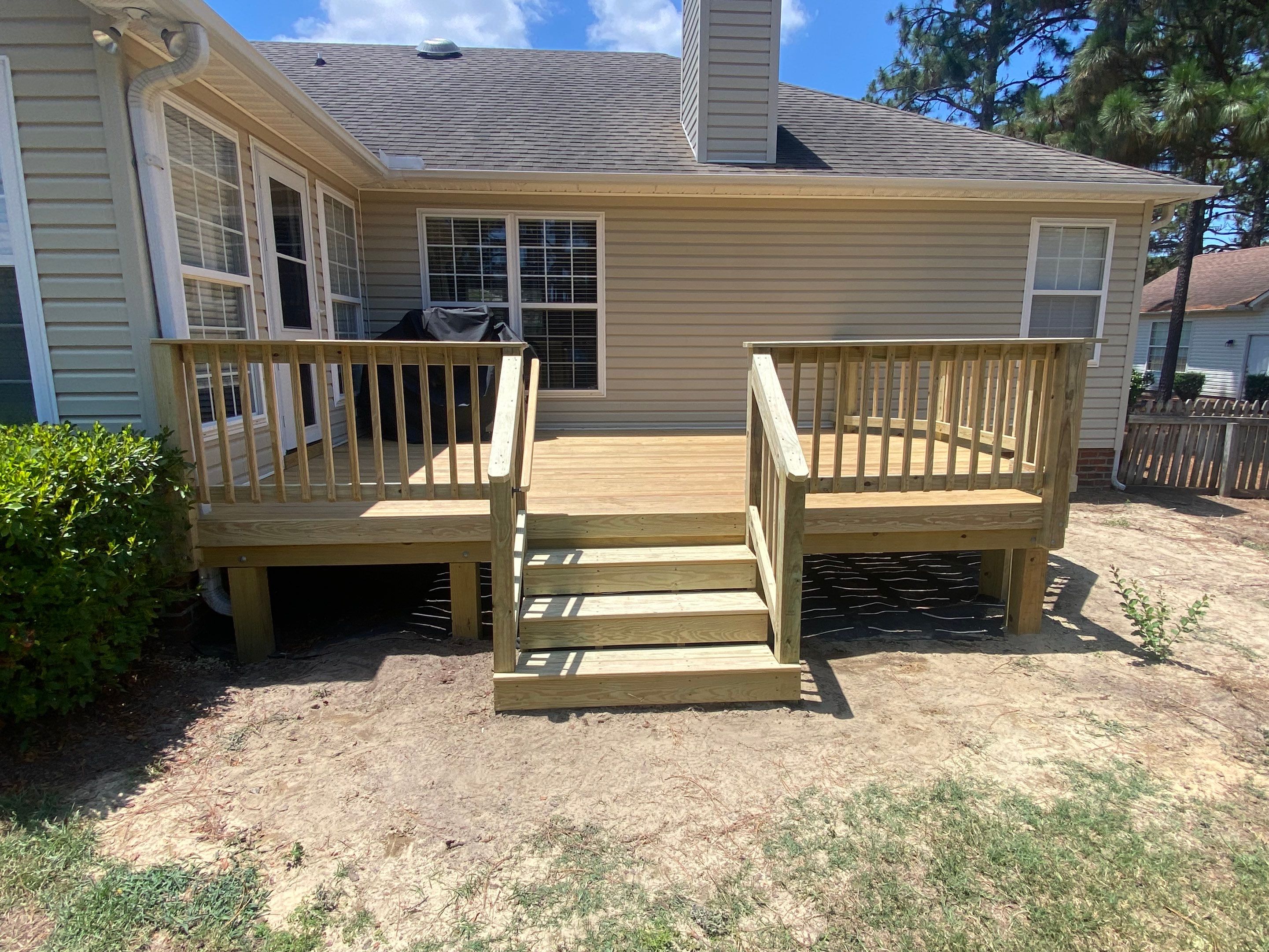 Custom Pressure-Treated Wood Deck with Central Stairs in Whispering Pines by The Remodeling Company